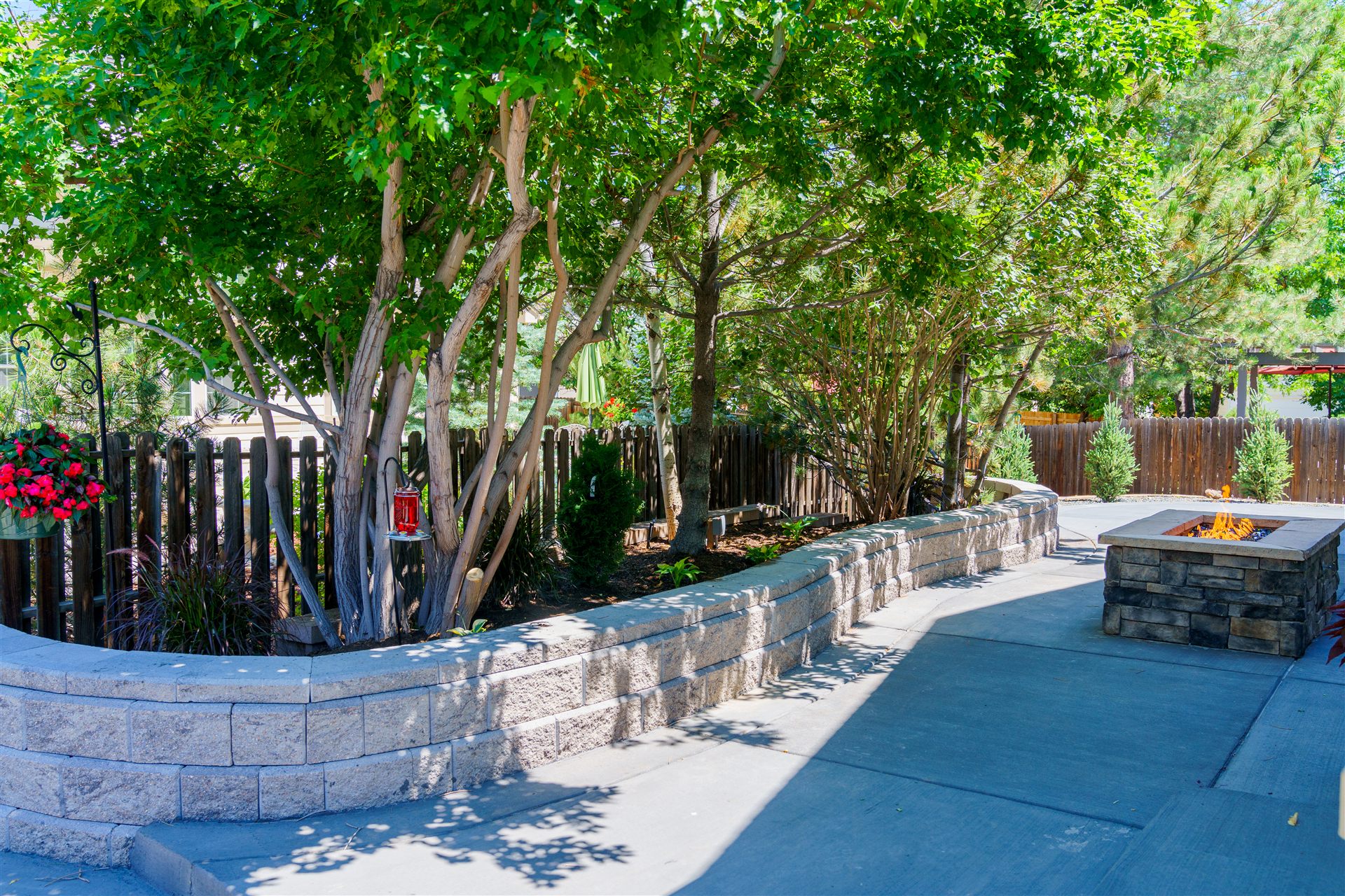 Curved block seat wall around planting beds on a concrete patio