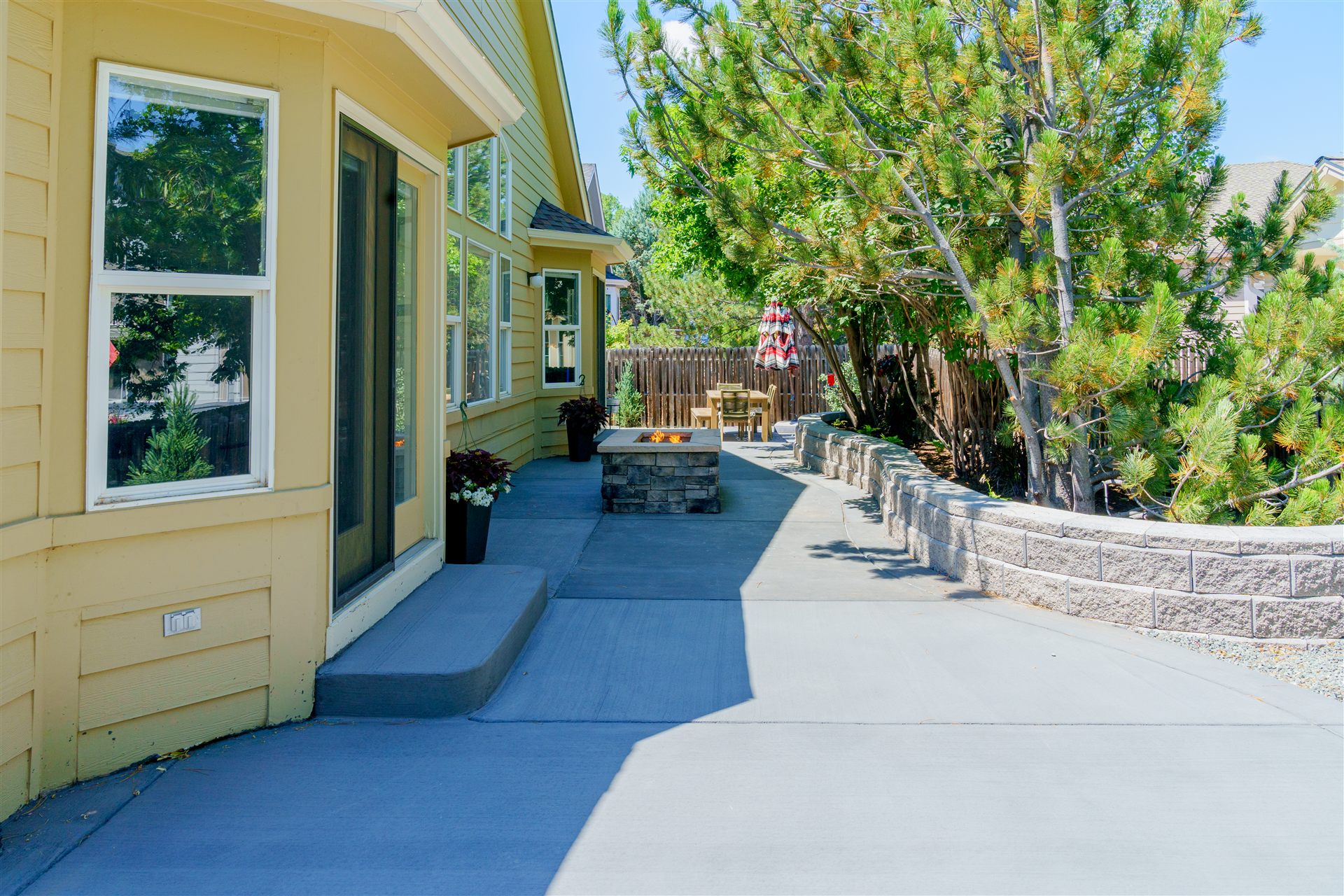Concrete patio running along the house beside a seat wall