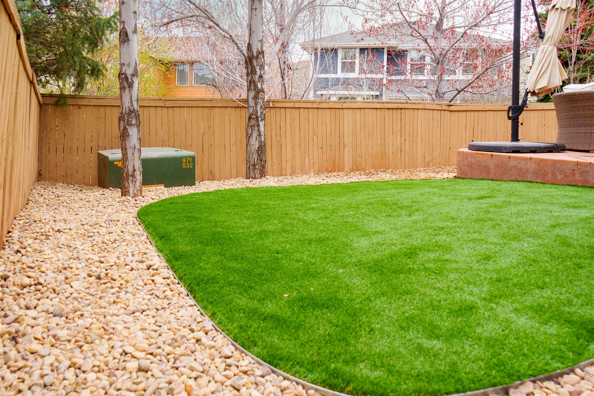 Curved synthetic turf lawn with a river rock border in Aurora, CO