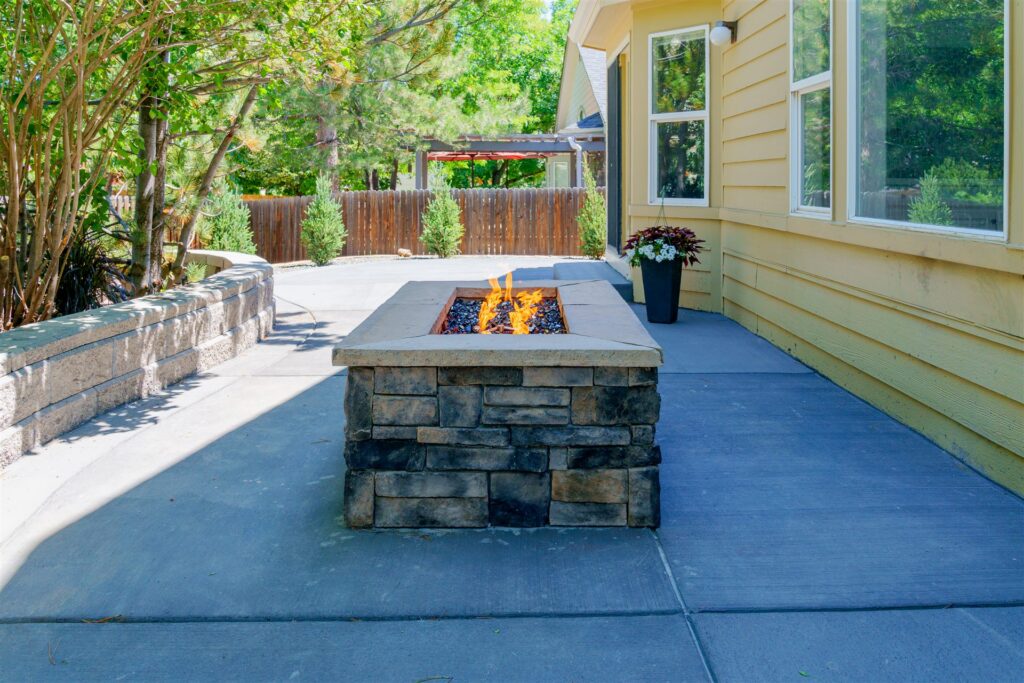 Concrete patio with a stone fire pit table and block seat wall in Aurora, CO