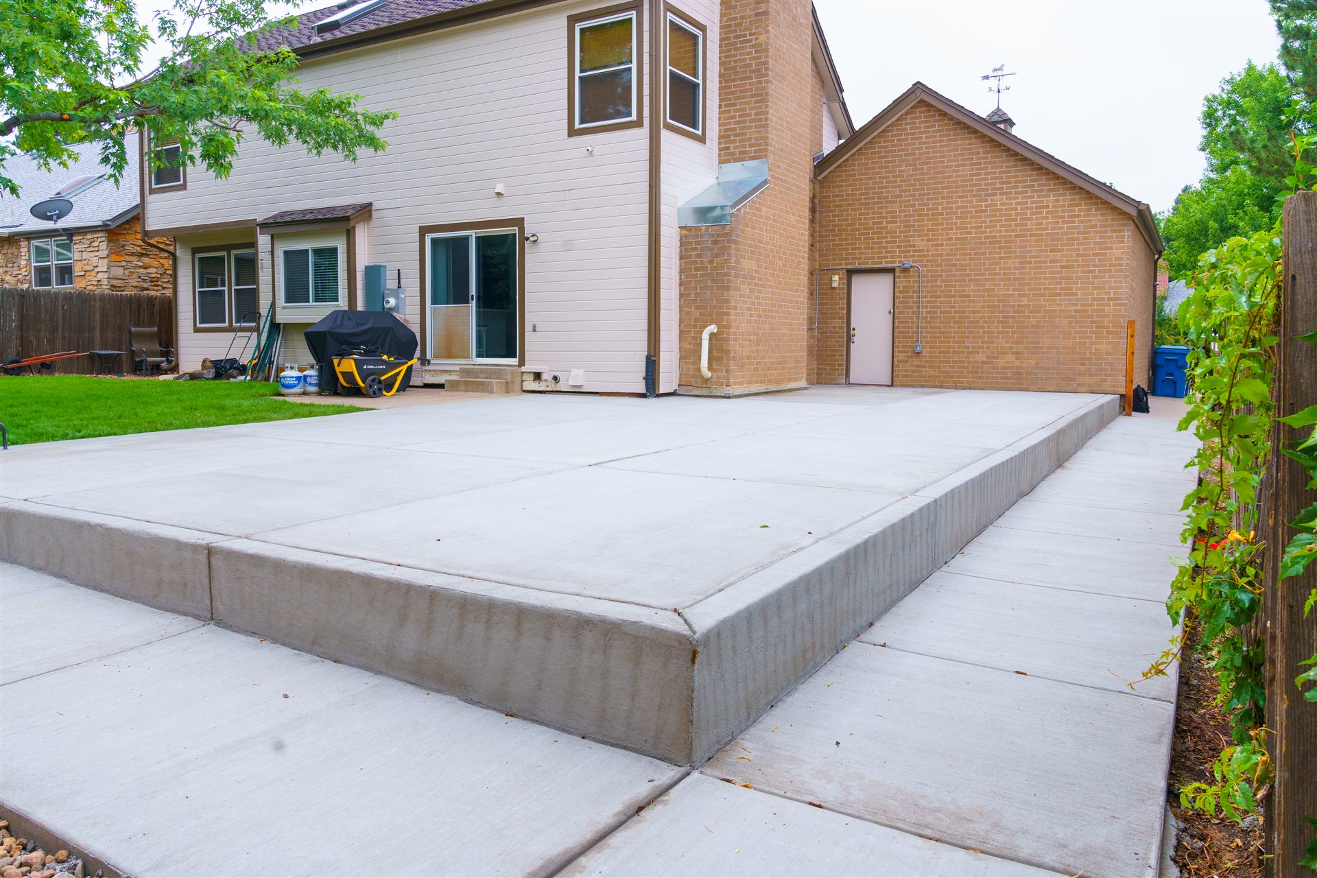 Large concrete patio with a step down behind a home in Aurora, CO