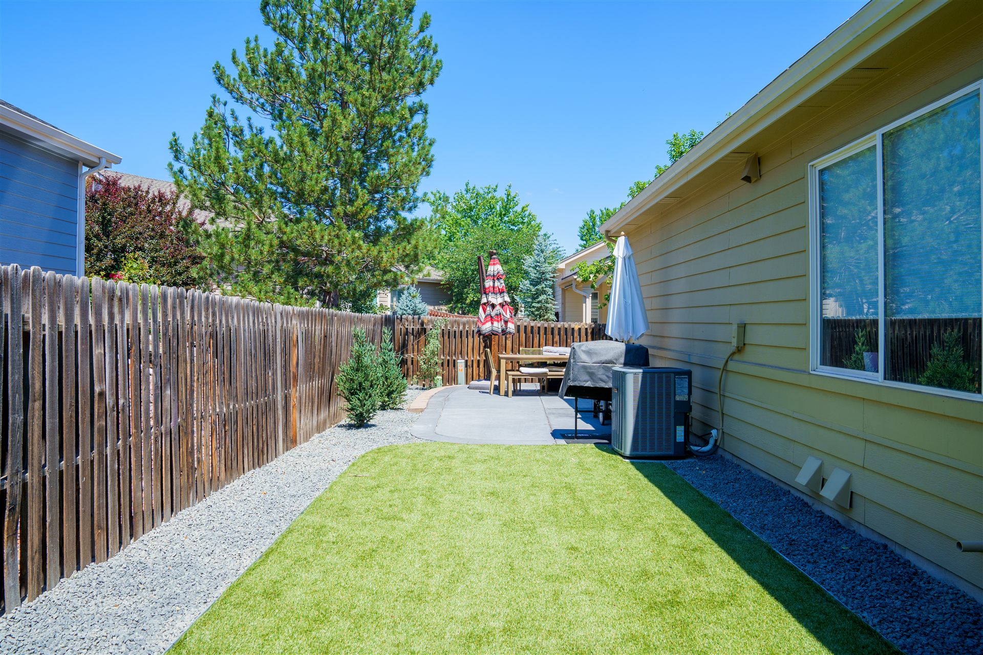 Synthetic turf and gray rock in a narrow side yard
