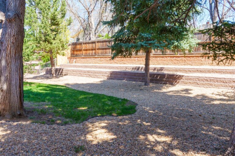 Block retaining walls along a back fence with rock landscaping in Brighton, CO