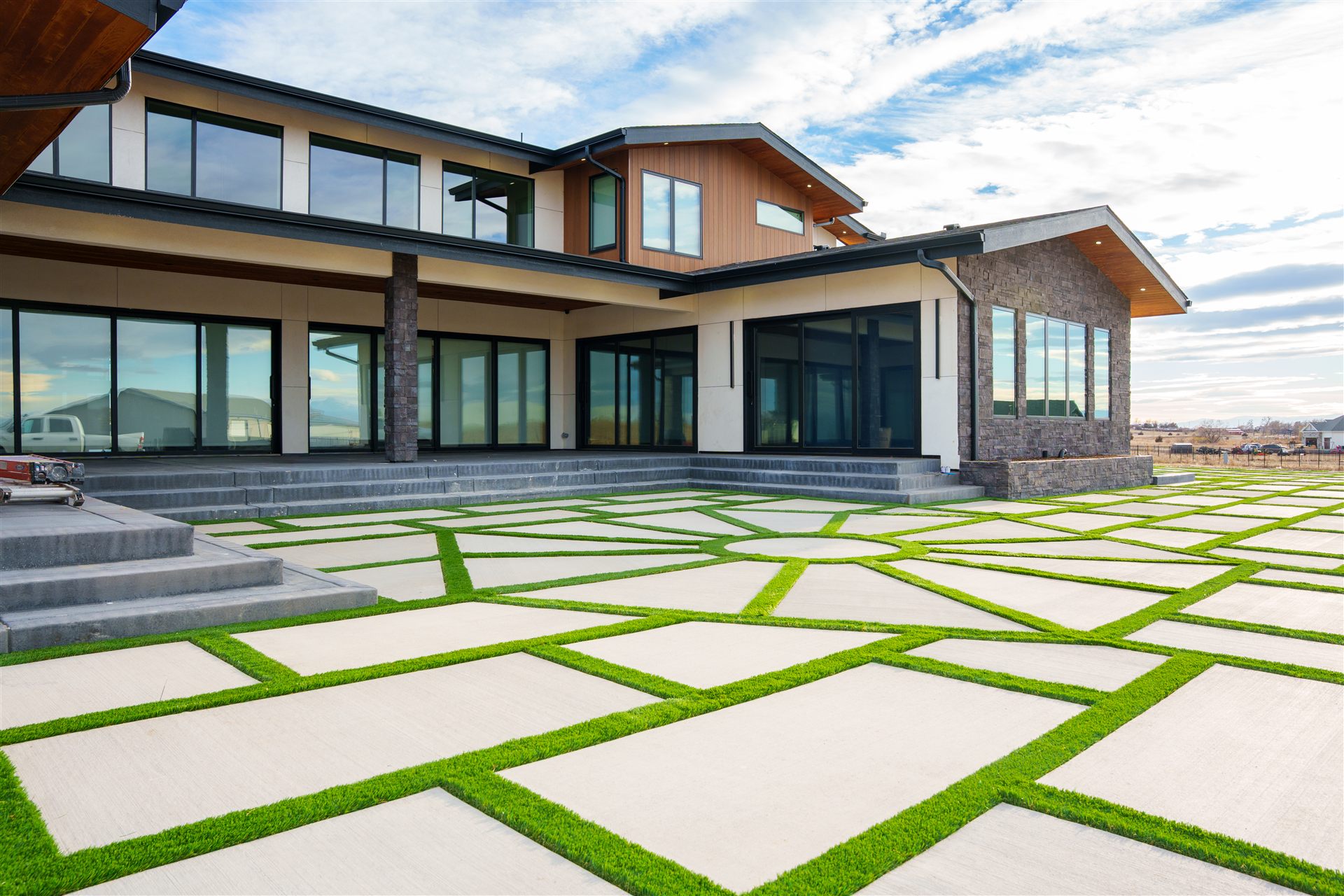 Concrete and turf grid patio across the back of a modern home
