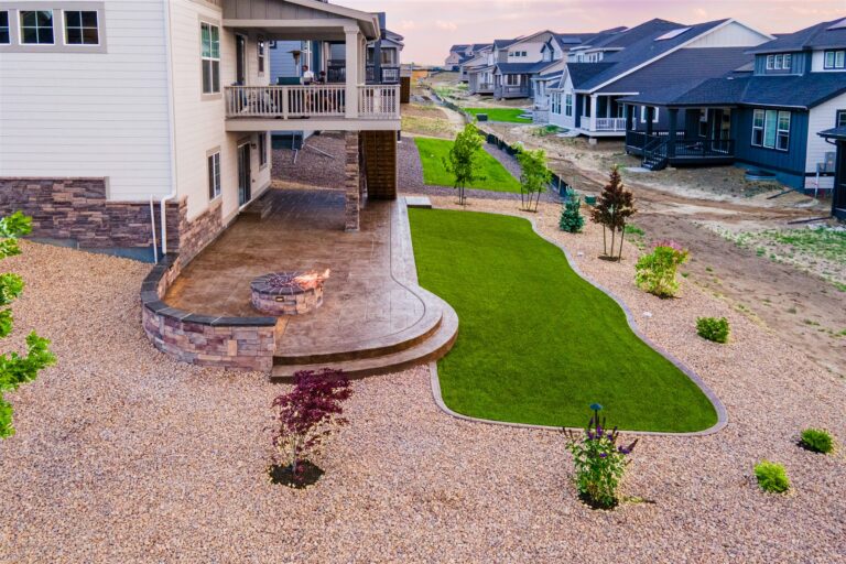 Fire pit and curved stone seat wall on a stamped concrete patio in Brighton, CO