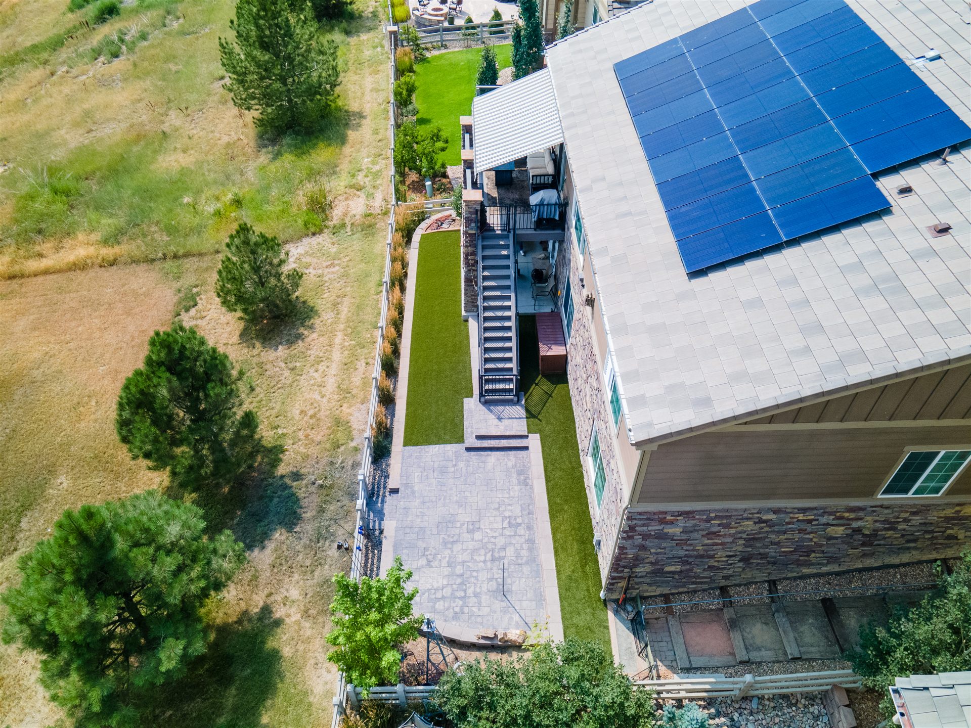 Aerial view of a narrow yard with a stamped patio backing onto open space