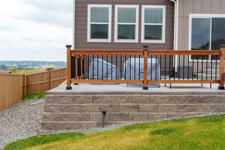 Capped block retaining wall with a wood and metal railing in Broomfield, CO