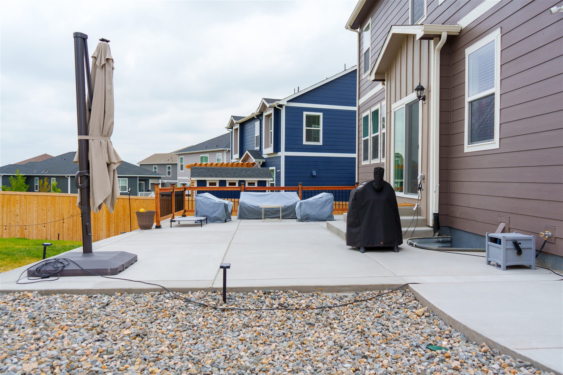 Concrete patio with a rock border behind a new home