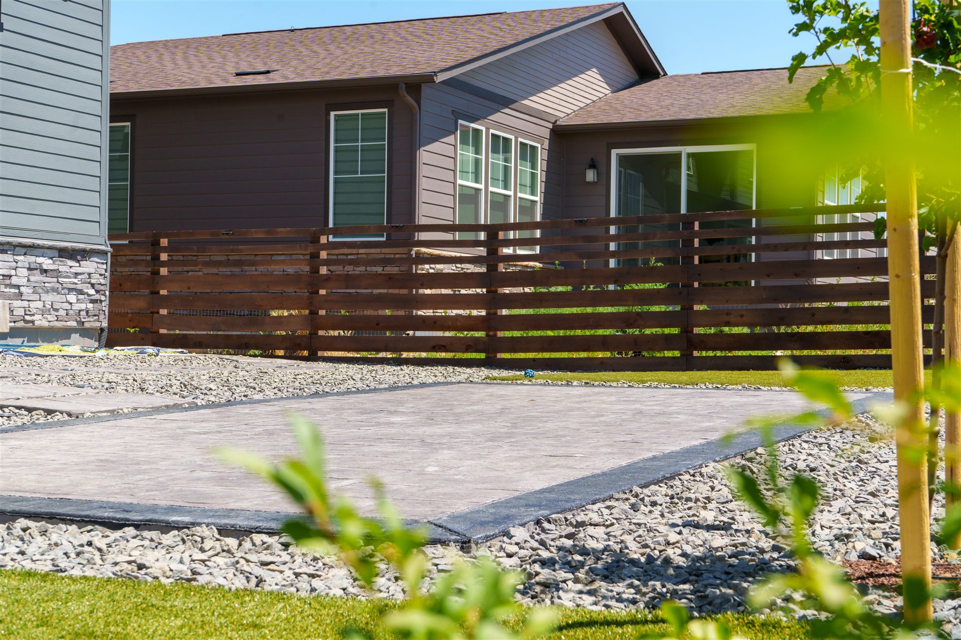 Stamped concrete patio in front of a horizontal wood fence