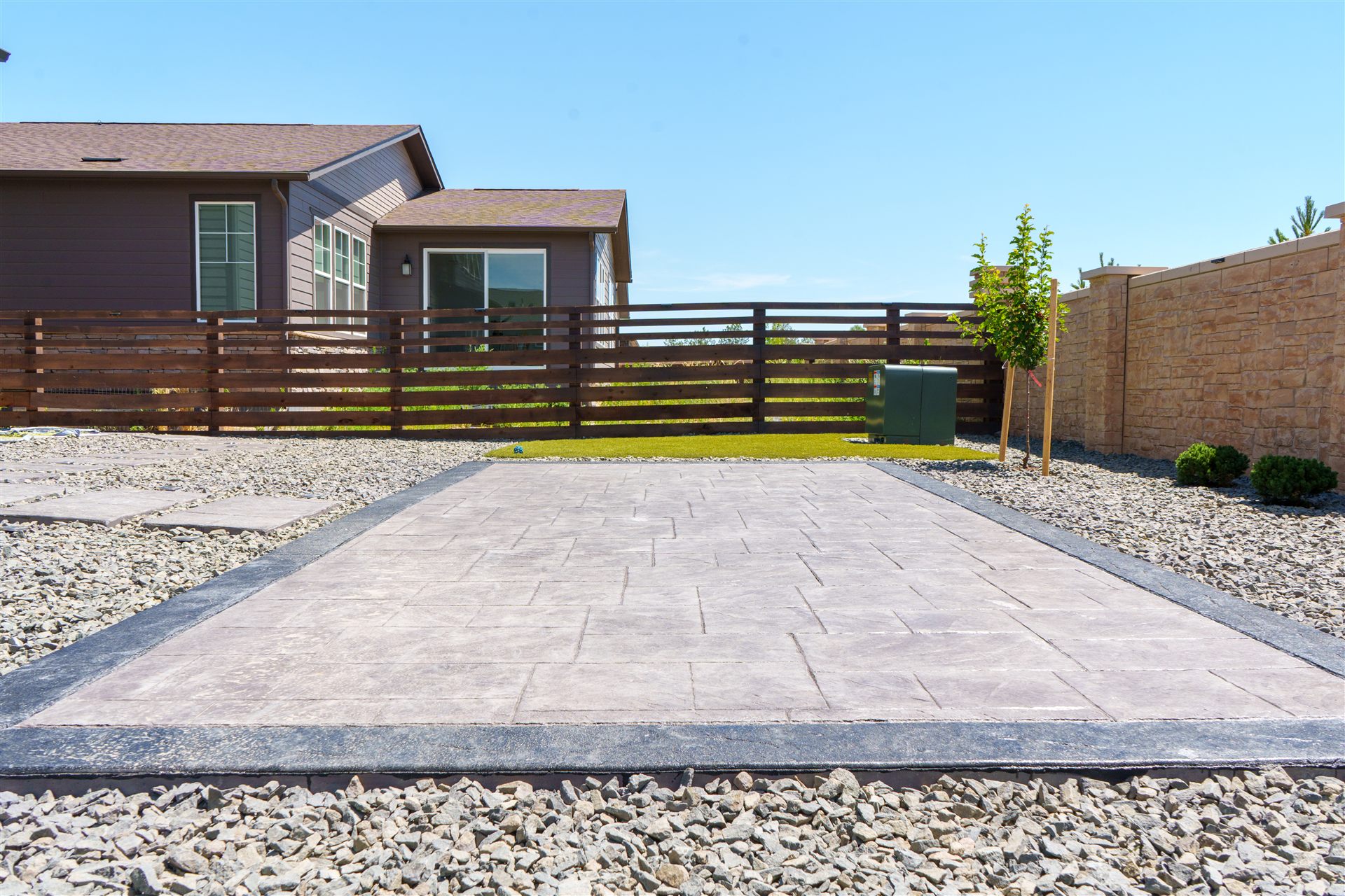 Stamped patio with a charcoal border surrounded by rock