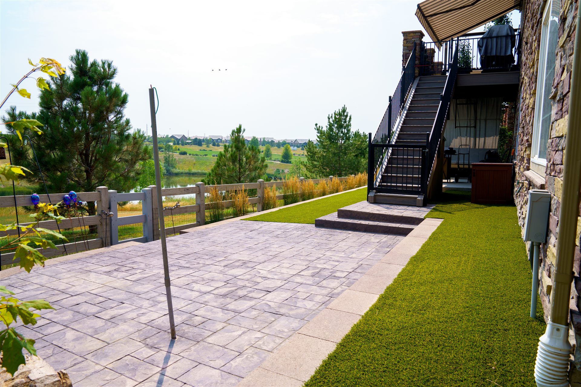 Stamped patio and turf below a deck staircase