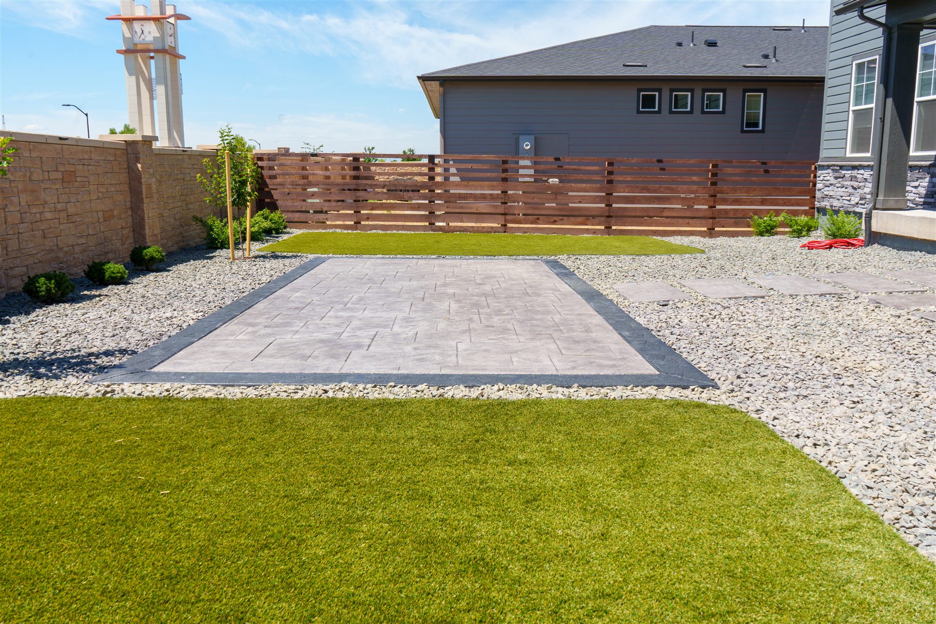 Stamped concrete patio with a charcoal border, rock and synthetic turf in Broomfield, CO
