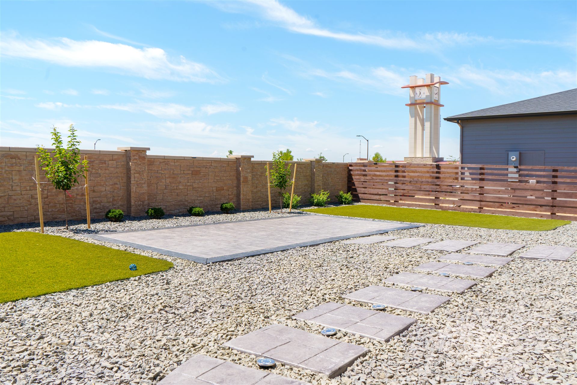 Concrete stepping pads through gray rock to a stamped patio
