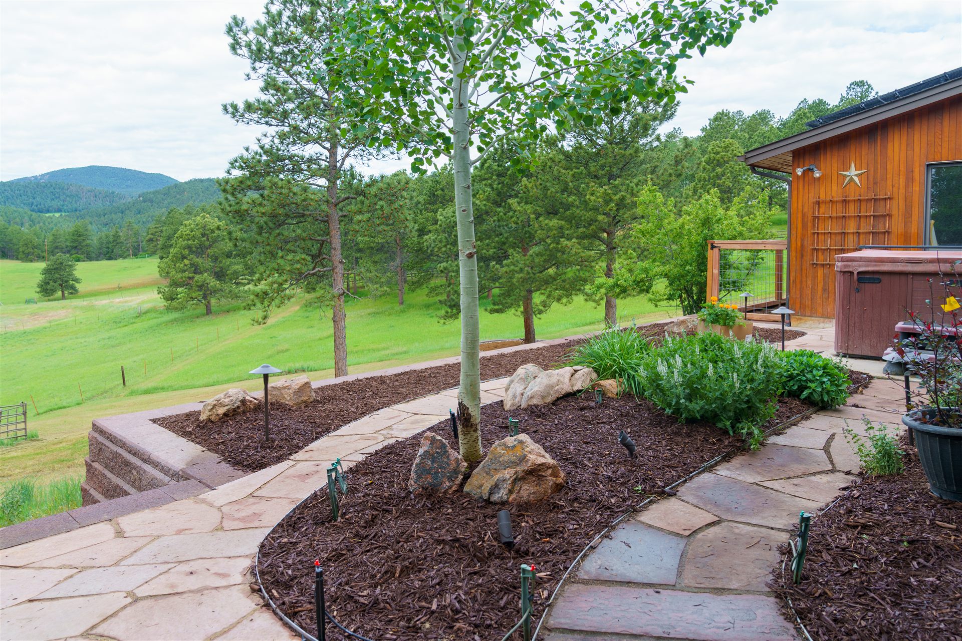 Flagstone walkway between mulch beds with boulders and path lights