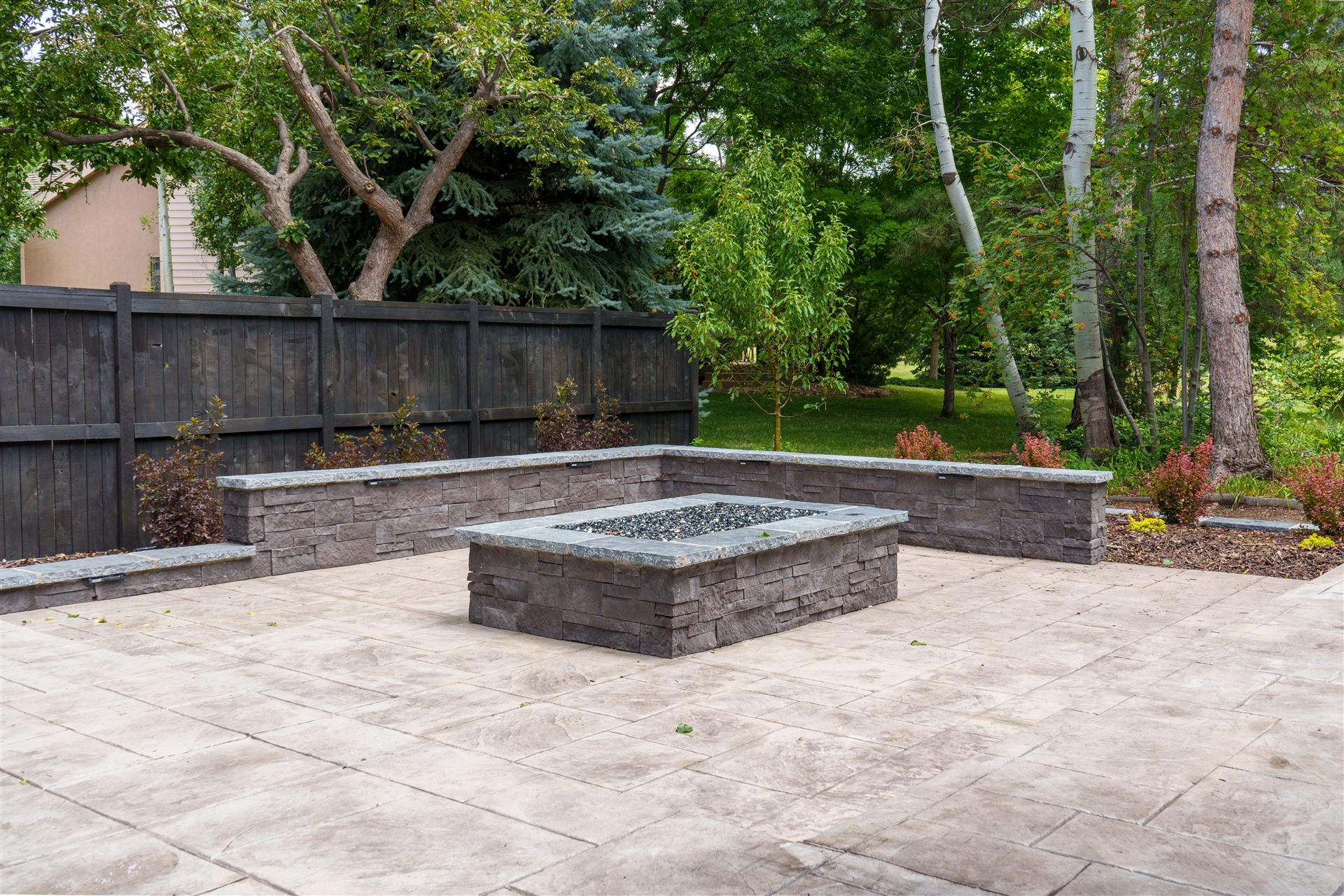 Rectangular stone fire pit on a stamped concrete patio