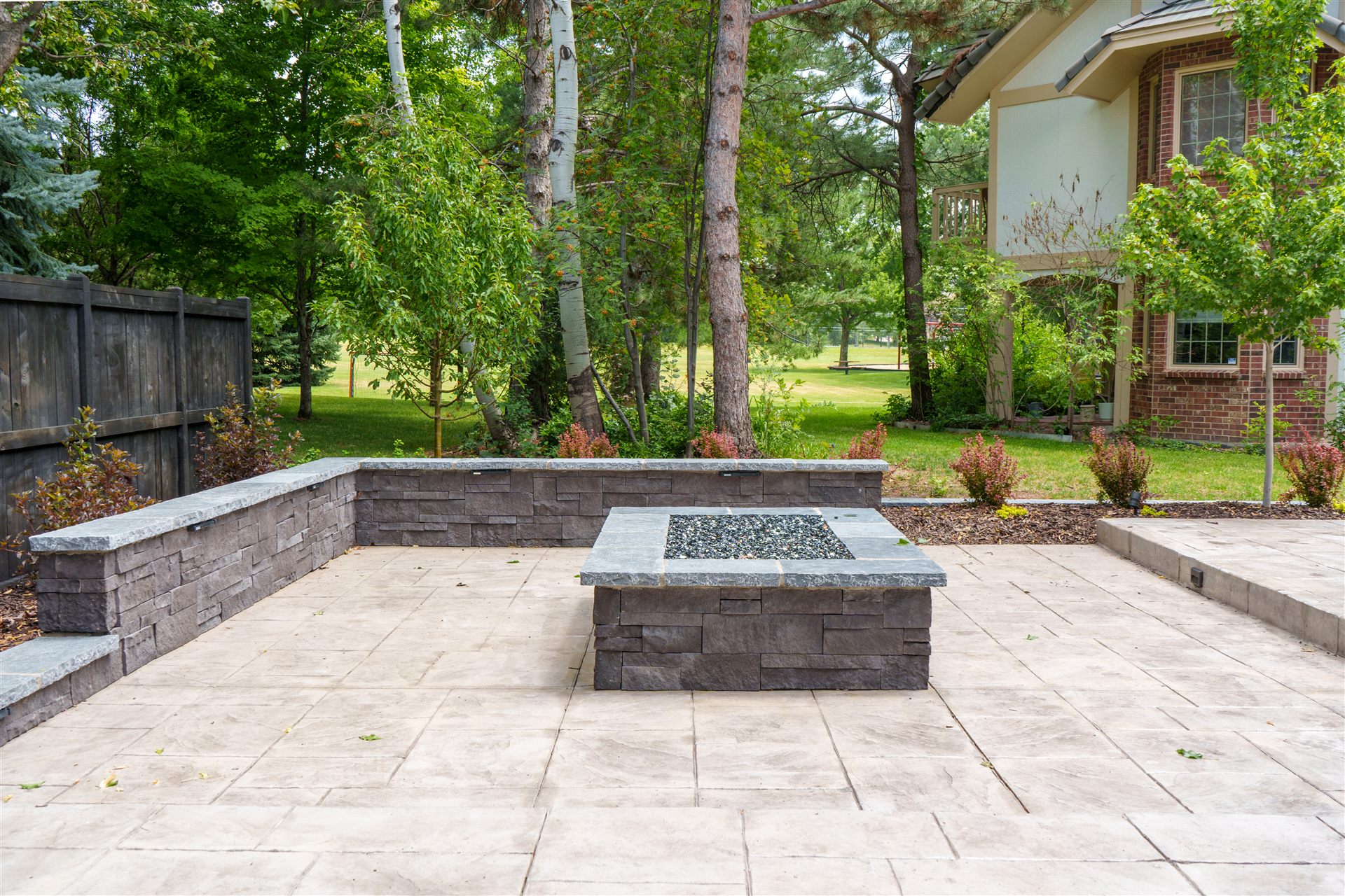 Stamped concrete patio with a stone fire pit and seat walls in Castle Rock, CO