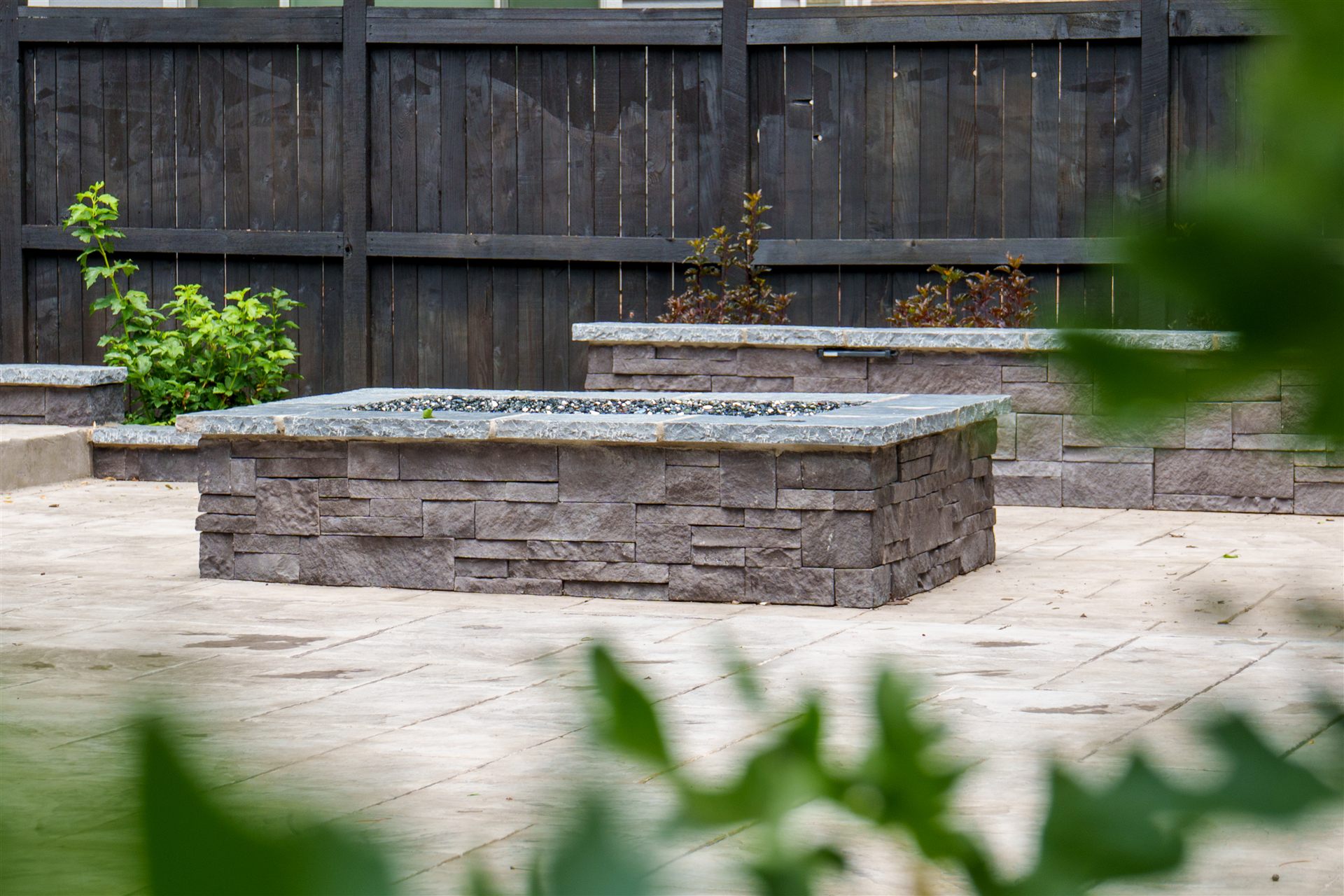 Stone veneer fire pit and raised planters on a patio in Castle Rock