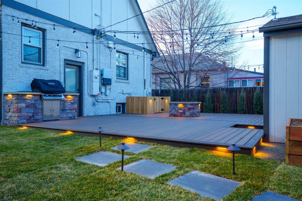 Composite deck with a stone fire pit, grill island and deck lighting in Centennial, CO