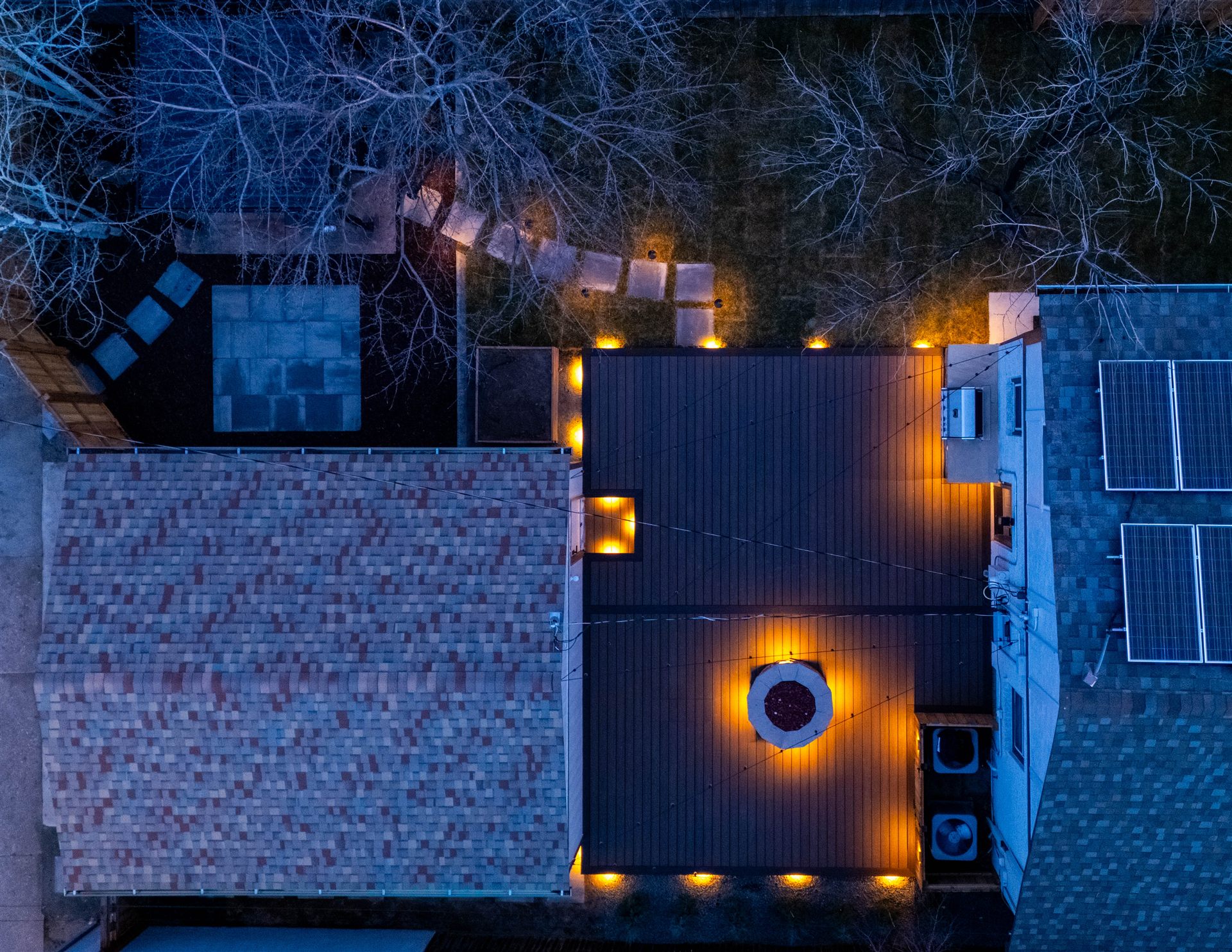 Aerial night view of a deck with a lit fire pit and stepping stones