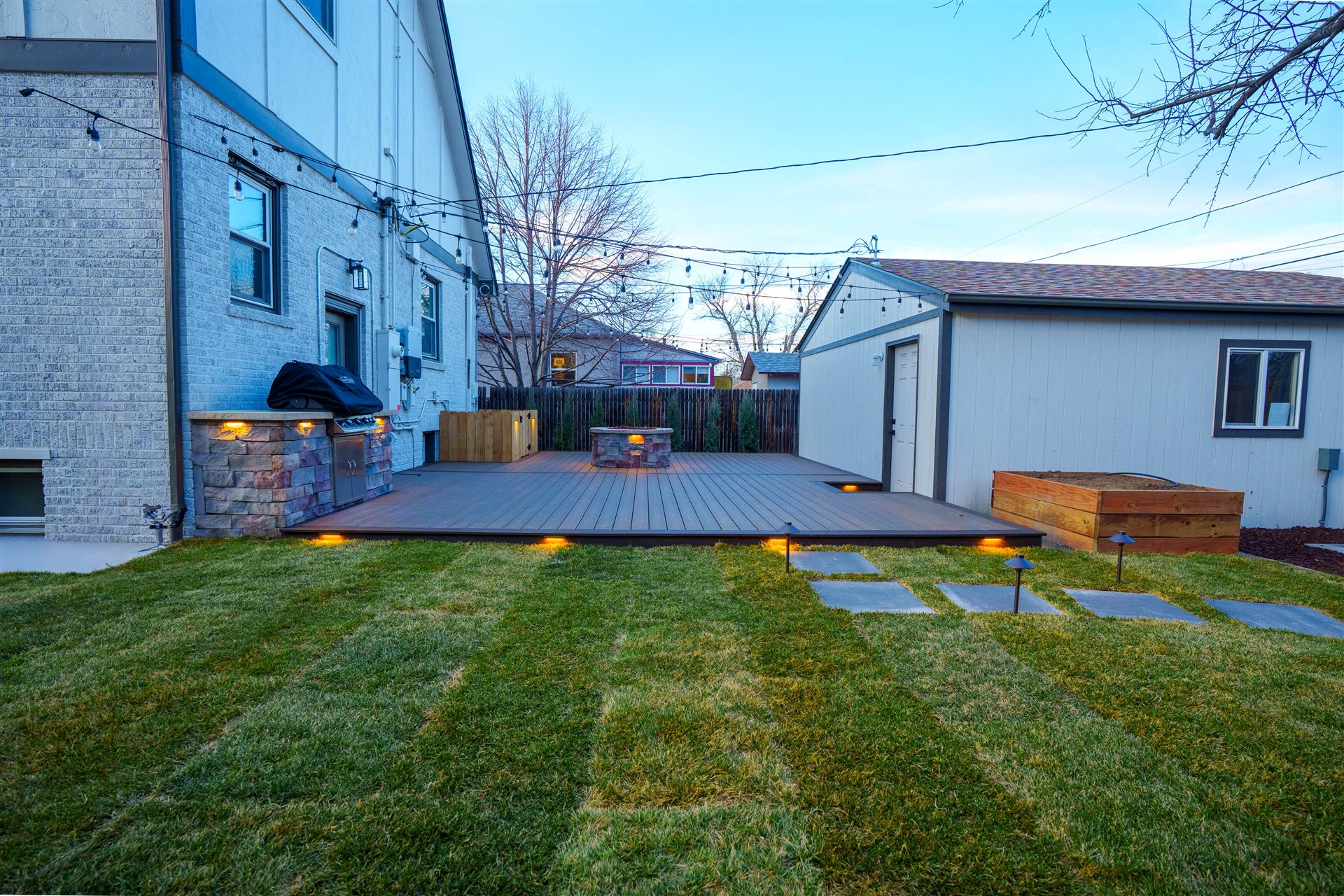 Composite deck with fresh sod, stepping stones and path lights in a Centennial backyard
