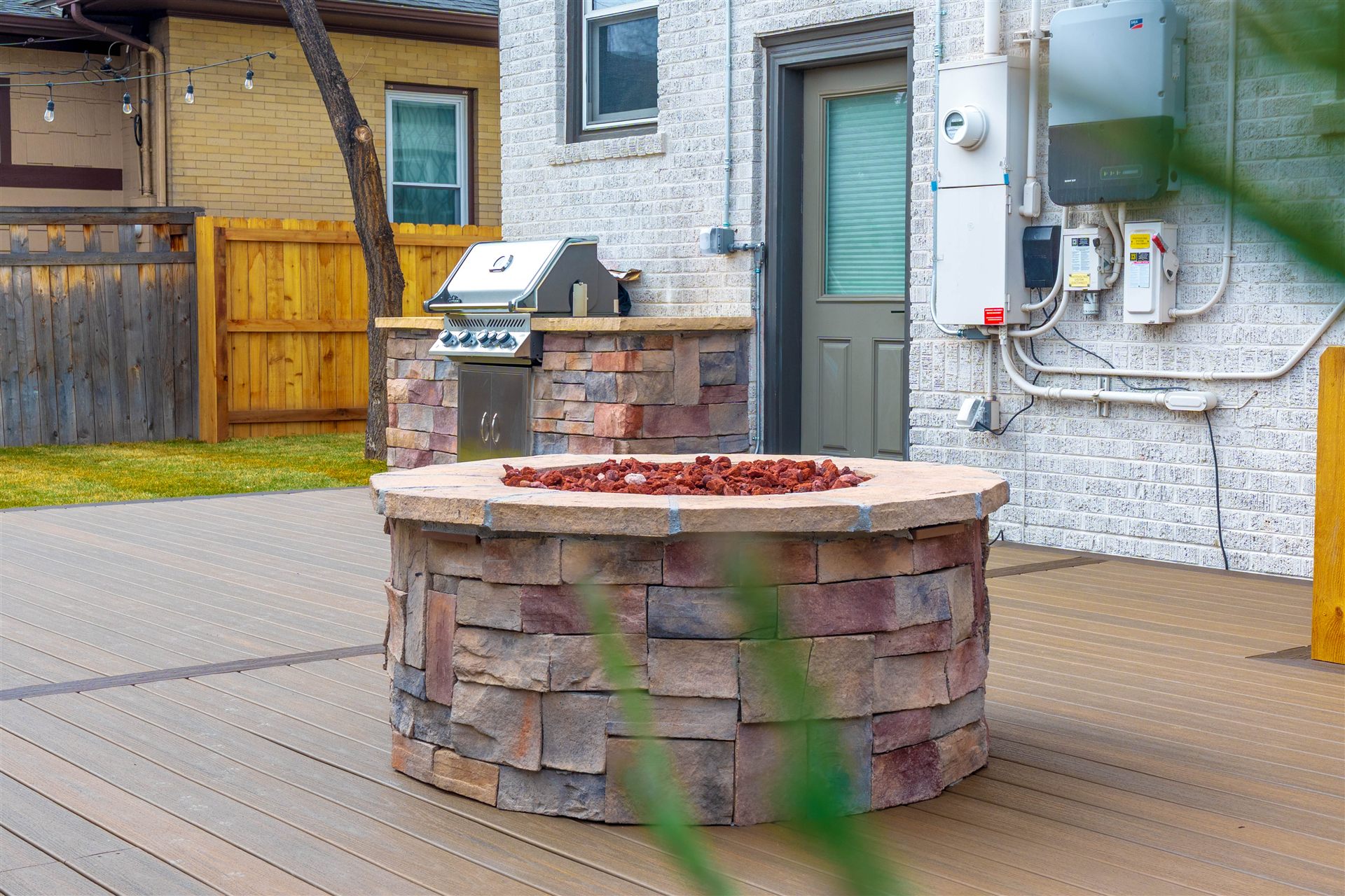 Stone fire pit with a stone-veneer grill island behind it