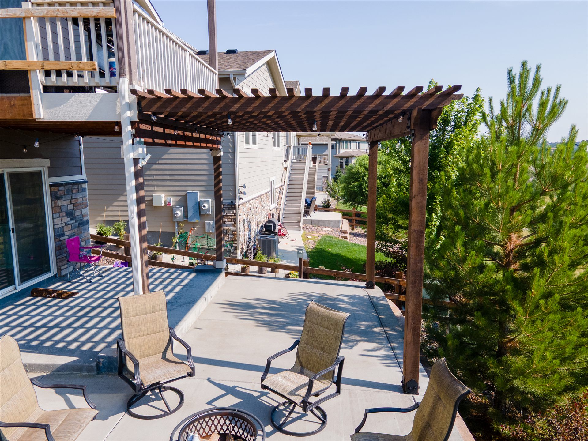 Concrete patio under a wood pergola attached to an upper deck