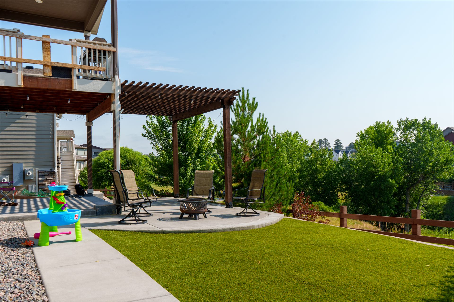 Wood pergola over a curved concrete patio with synthetic turf in Centennial, CO