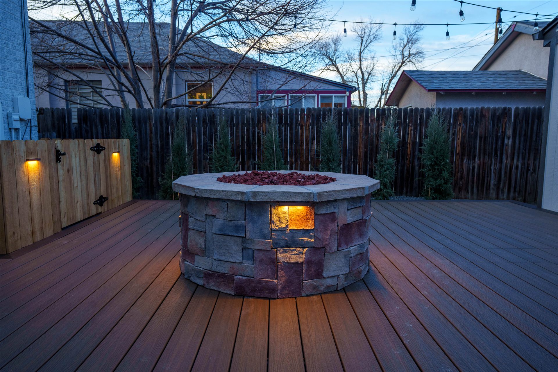 Round stone fire pit with lava rock on a composite deck