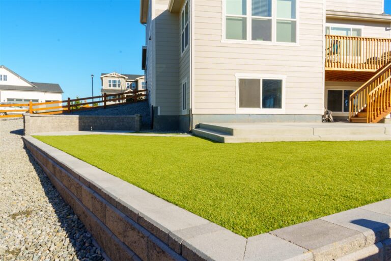 Capped block retaining wall framing a synthetic turf yard in Centennial, CO