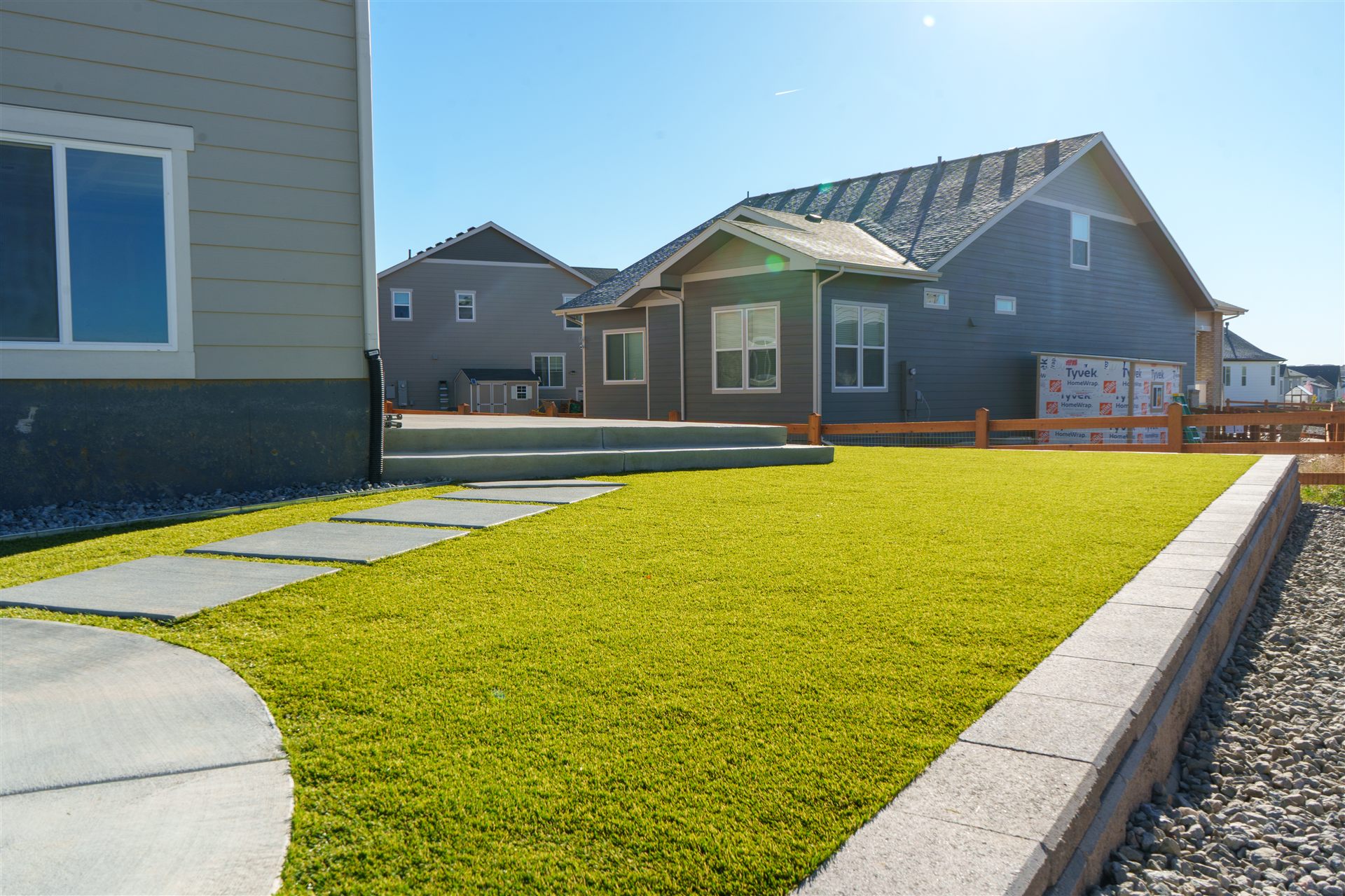 Concrete stepping pads across a synthetic turf lawn