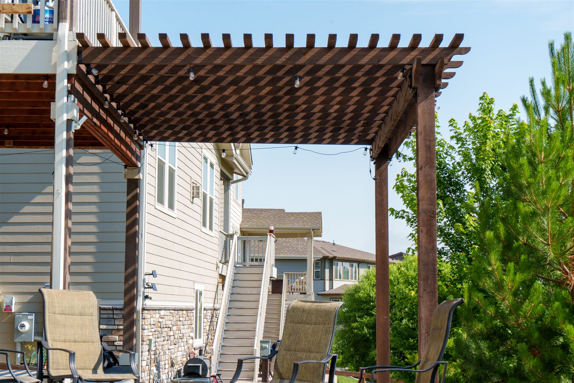 Wood pergola with string lights next to a walkout basement