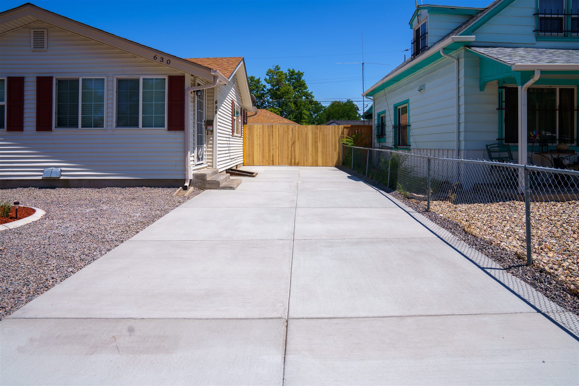 Concrete driveway leading to a new wood gate