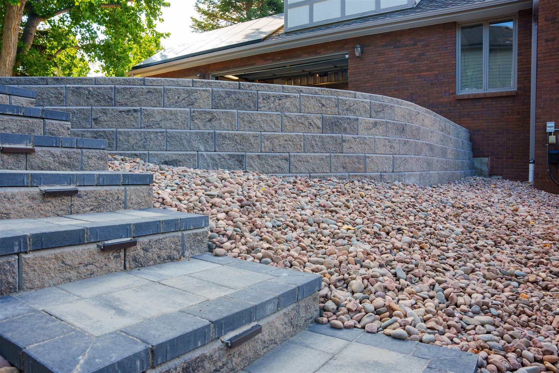 Block steps with river rock beside a curved retaining wall