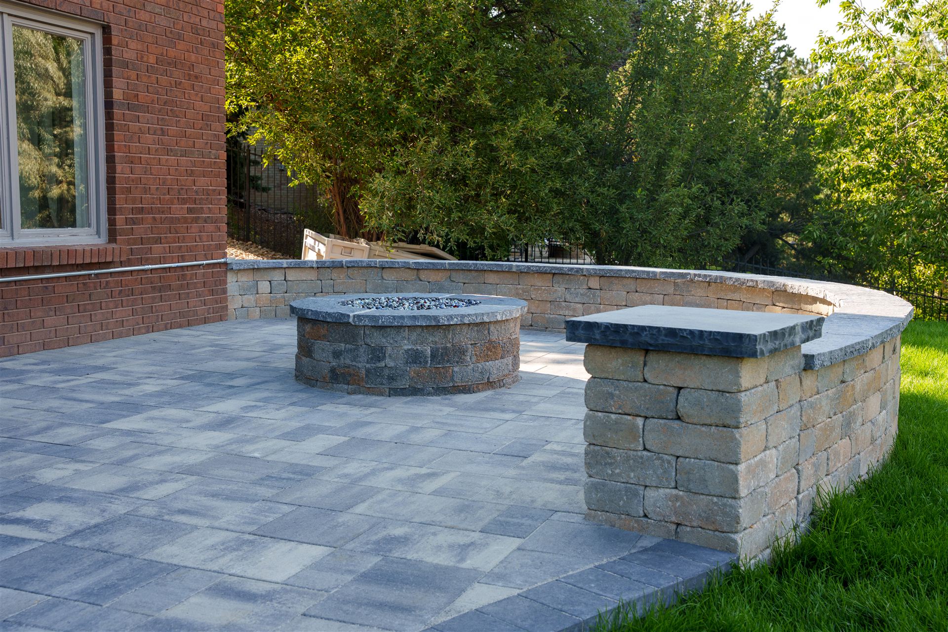 Paver patio with a round stone fire pit and curved seat wall in Littleton, CO