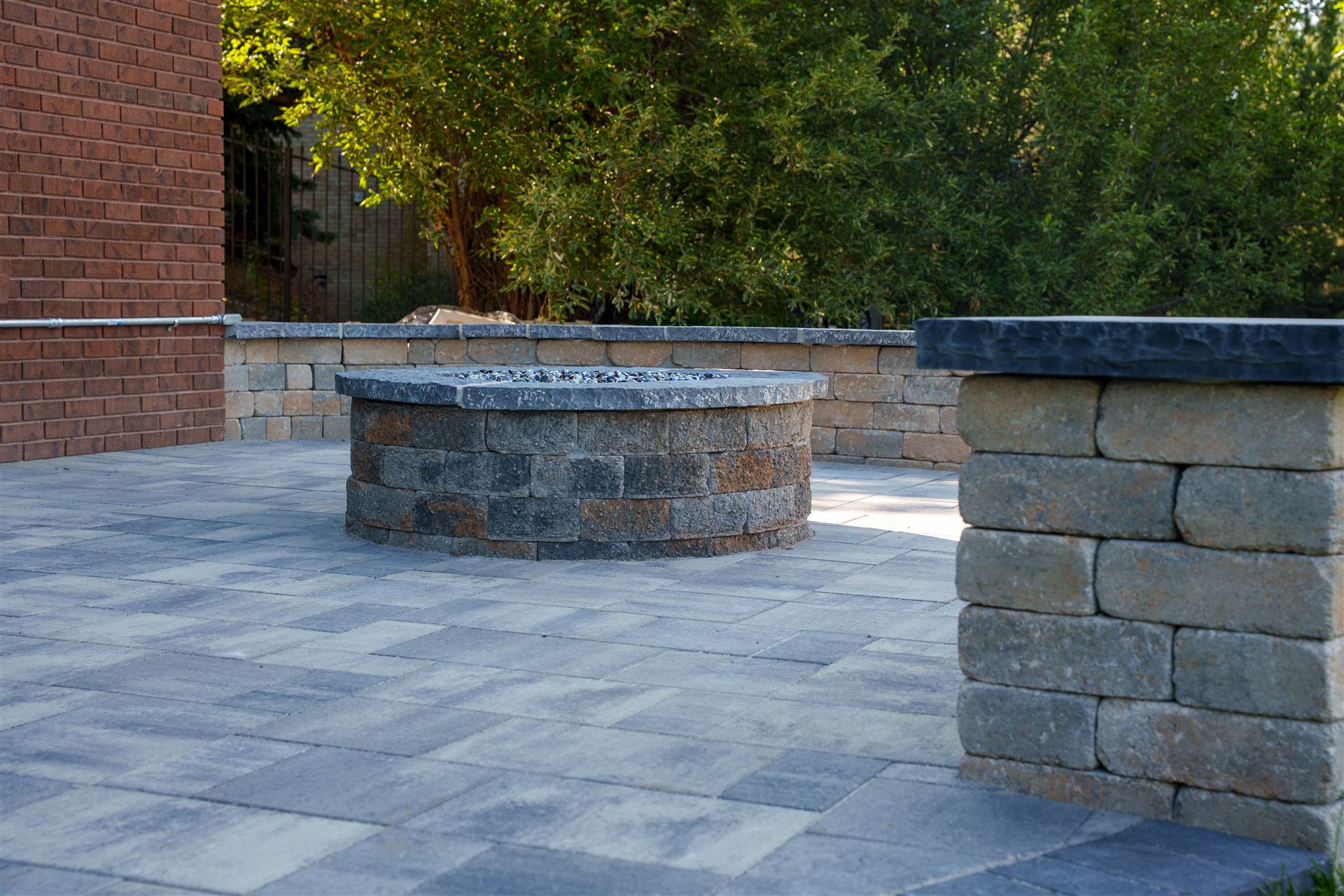 Stone pillar and seat wall on a gray paver patio