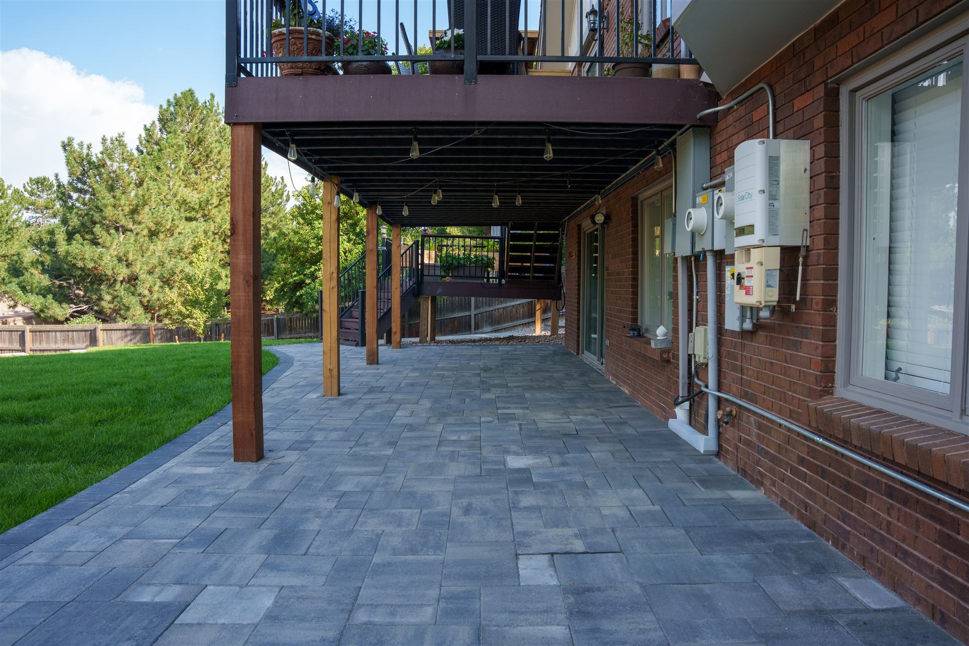 Paver patio under a raised deck along a brick home