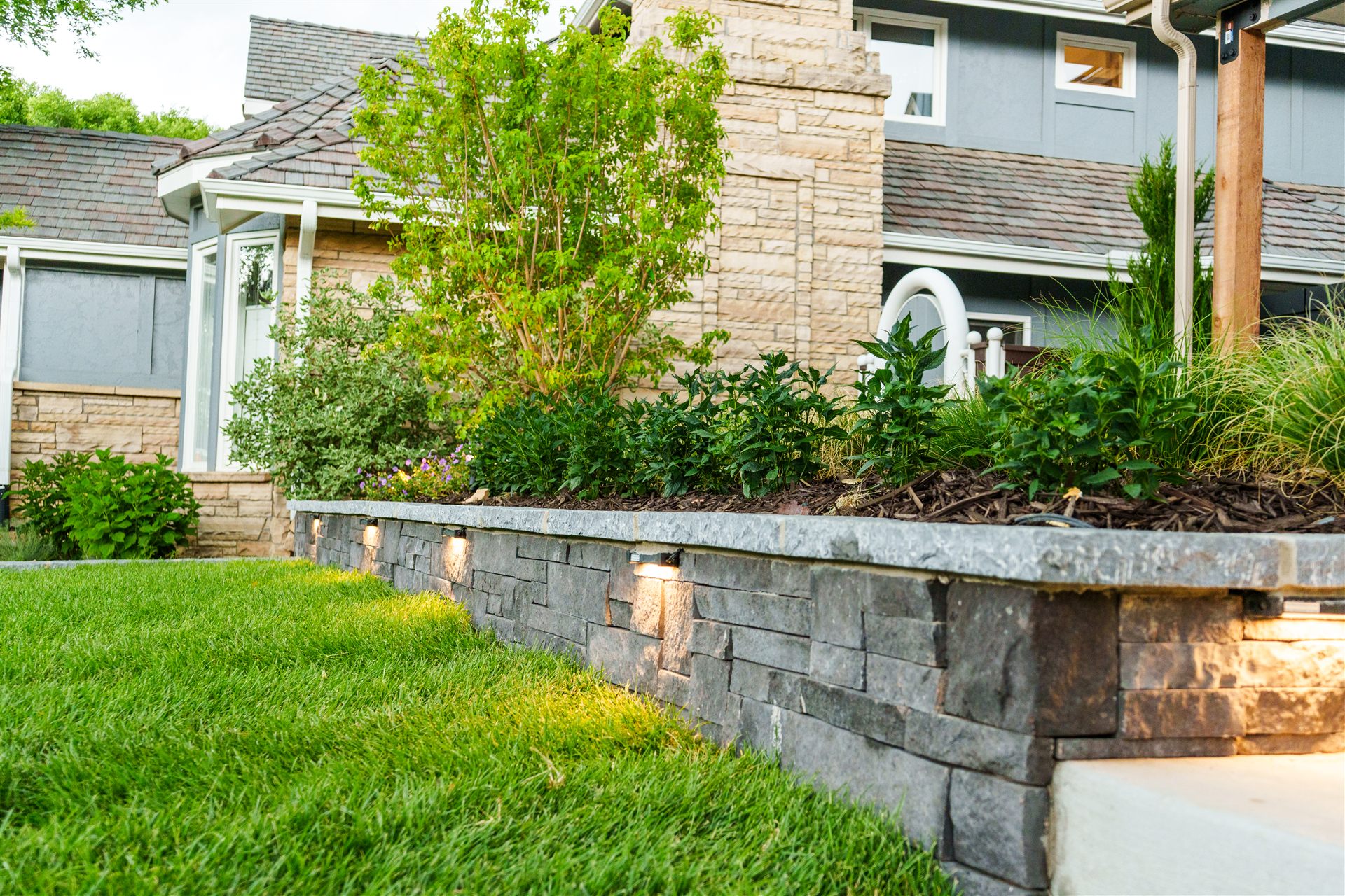 Stone planter wall with lights under the cap and fresh sod