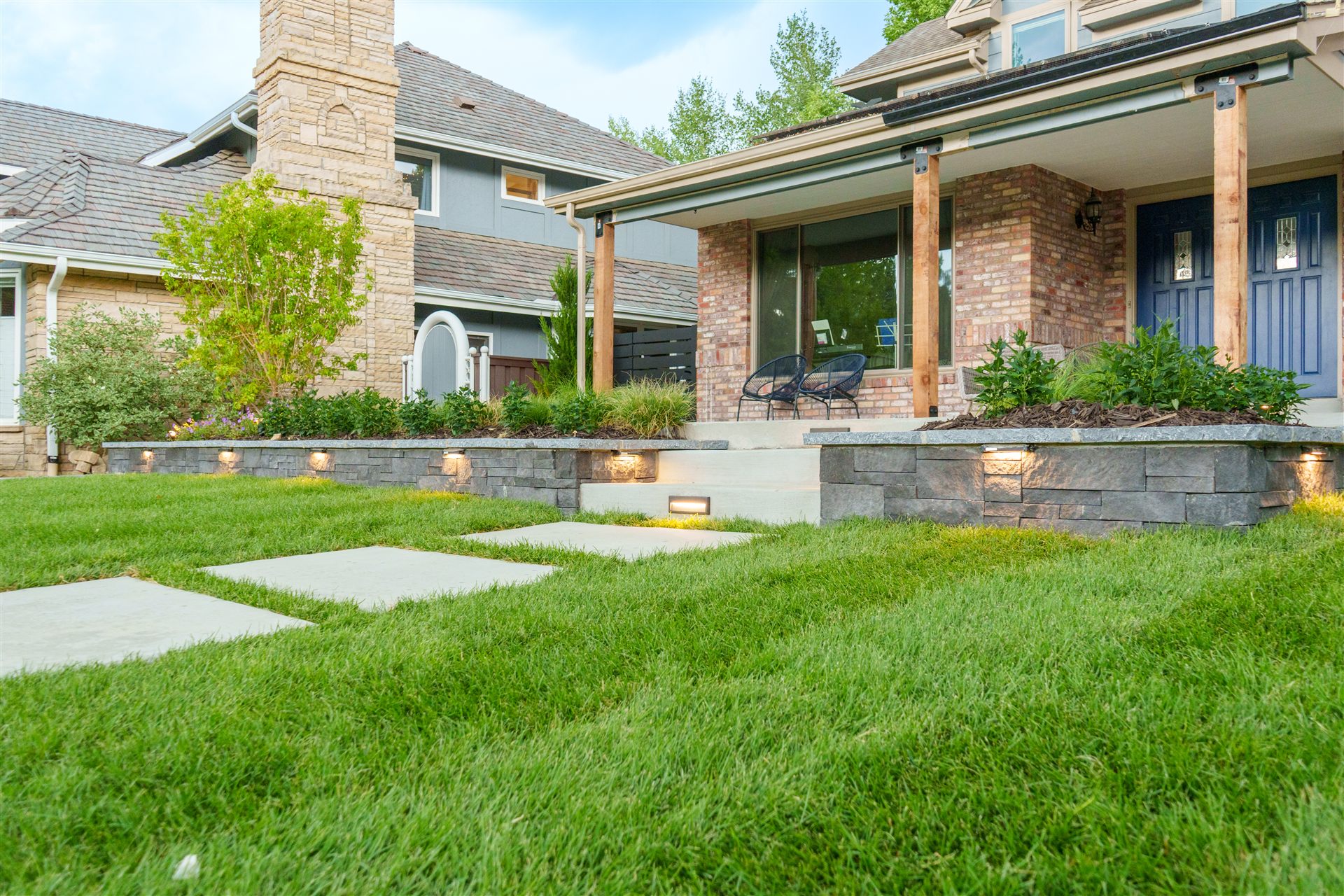 Low stone retaining wall with built-in lights along a front porch