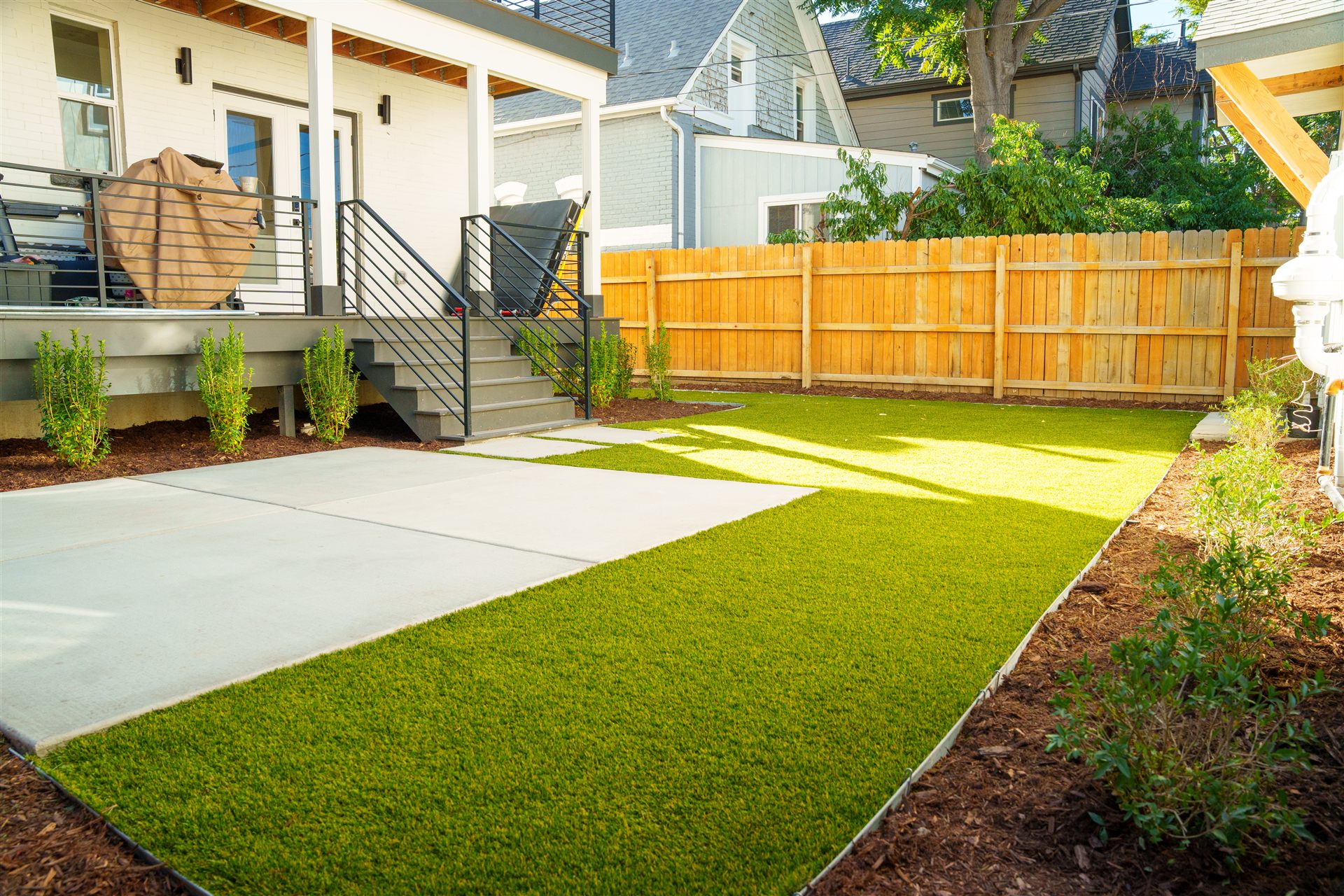 Synthetic turf backyard with a mulch bed and shrubs