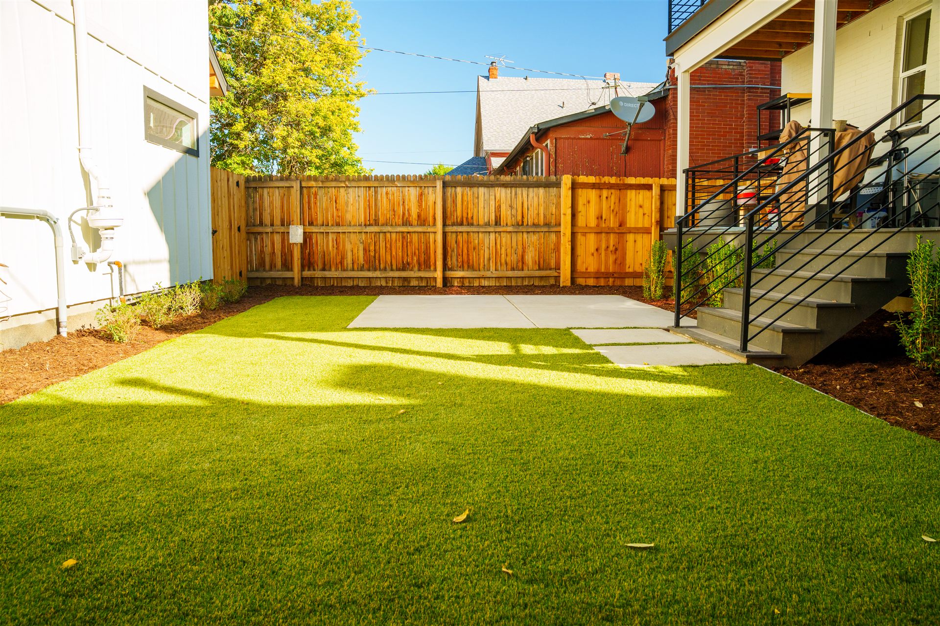 Turf lawn and concrete pad in a fenced backyard
