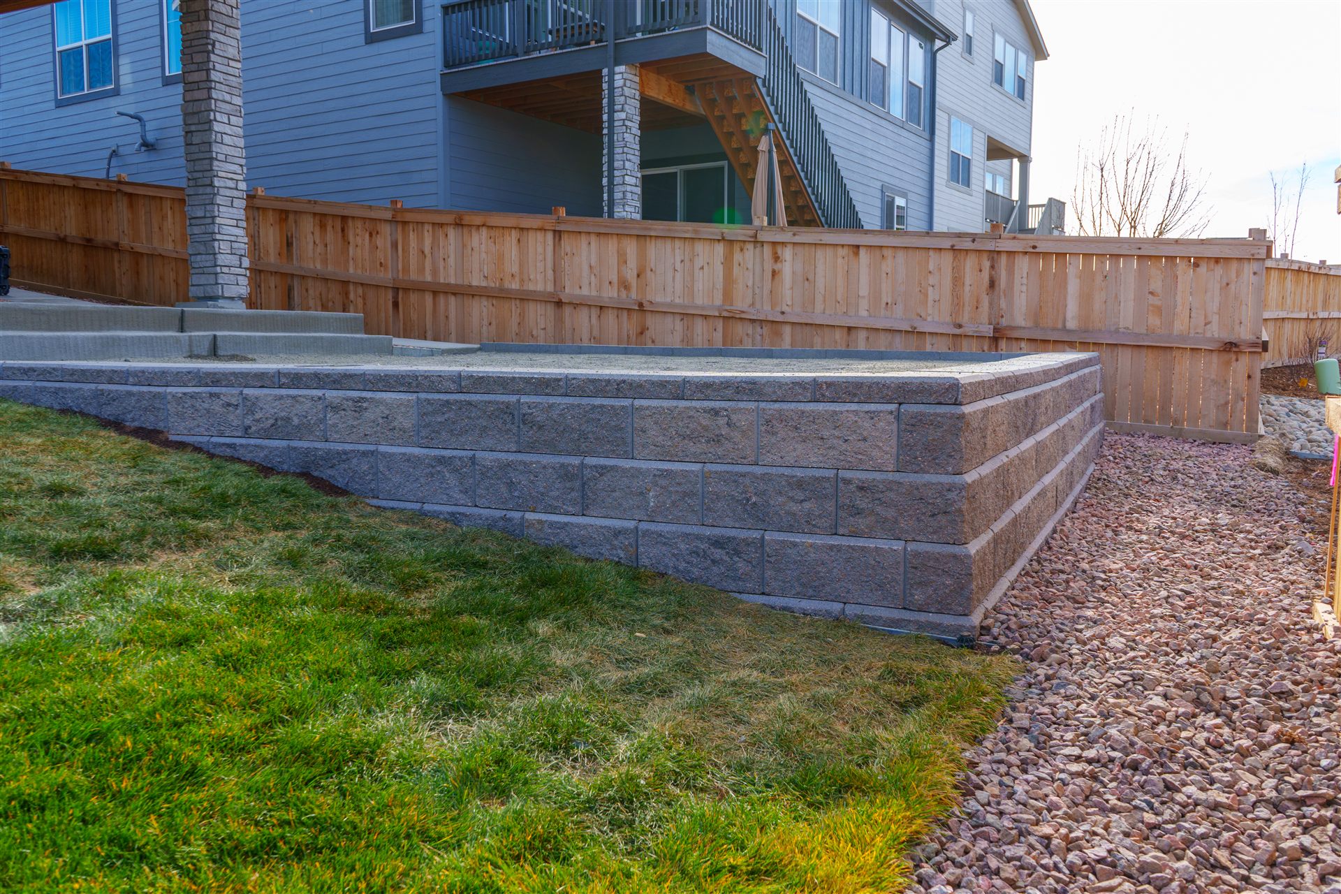 Block retaining wall next to a lawn and red rock