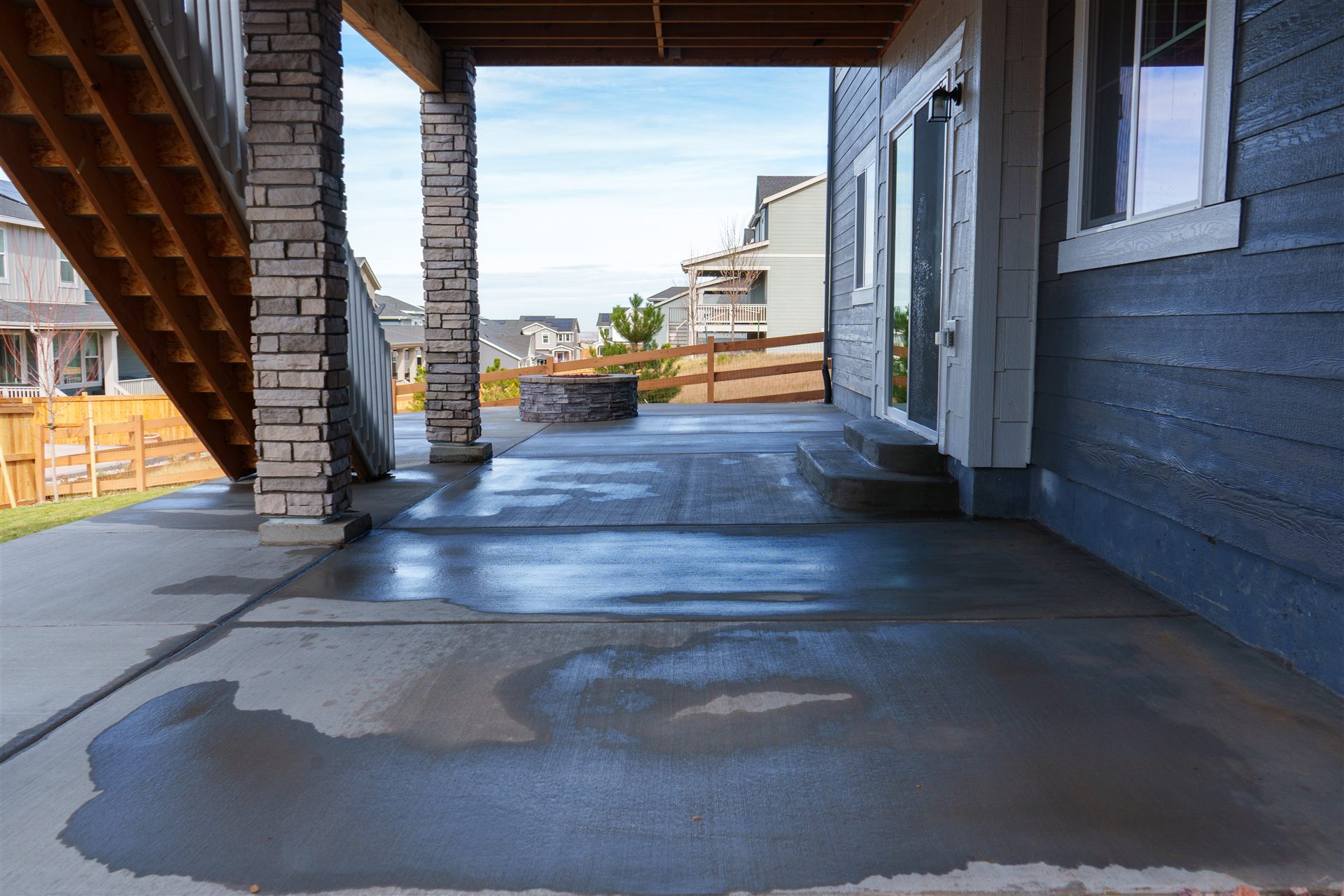 New concrete patio under a deck with stone columns