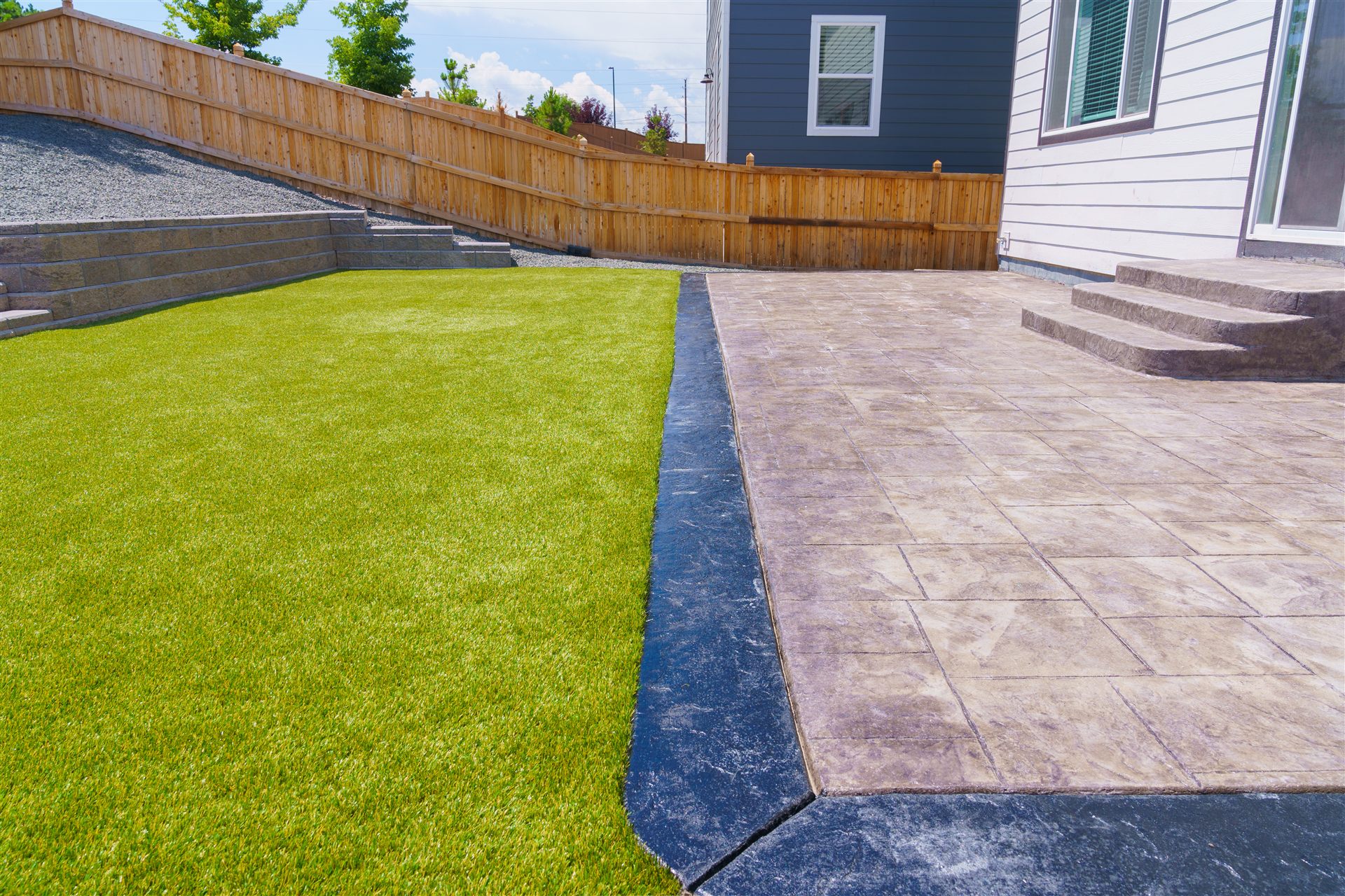 Stamped concrete patio with a charcoal border next to synthetic turf
