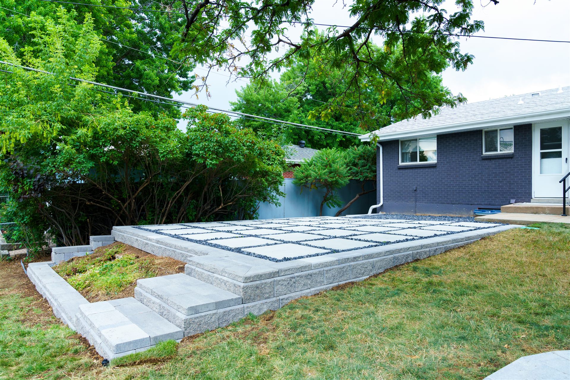 Block retaining wall and wide block steps below a raised patio