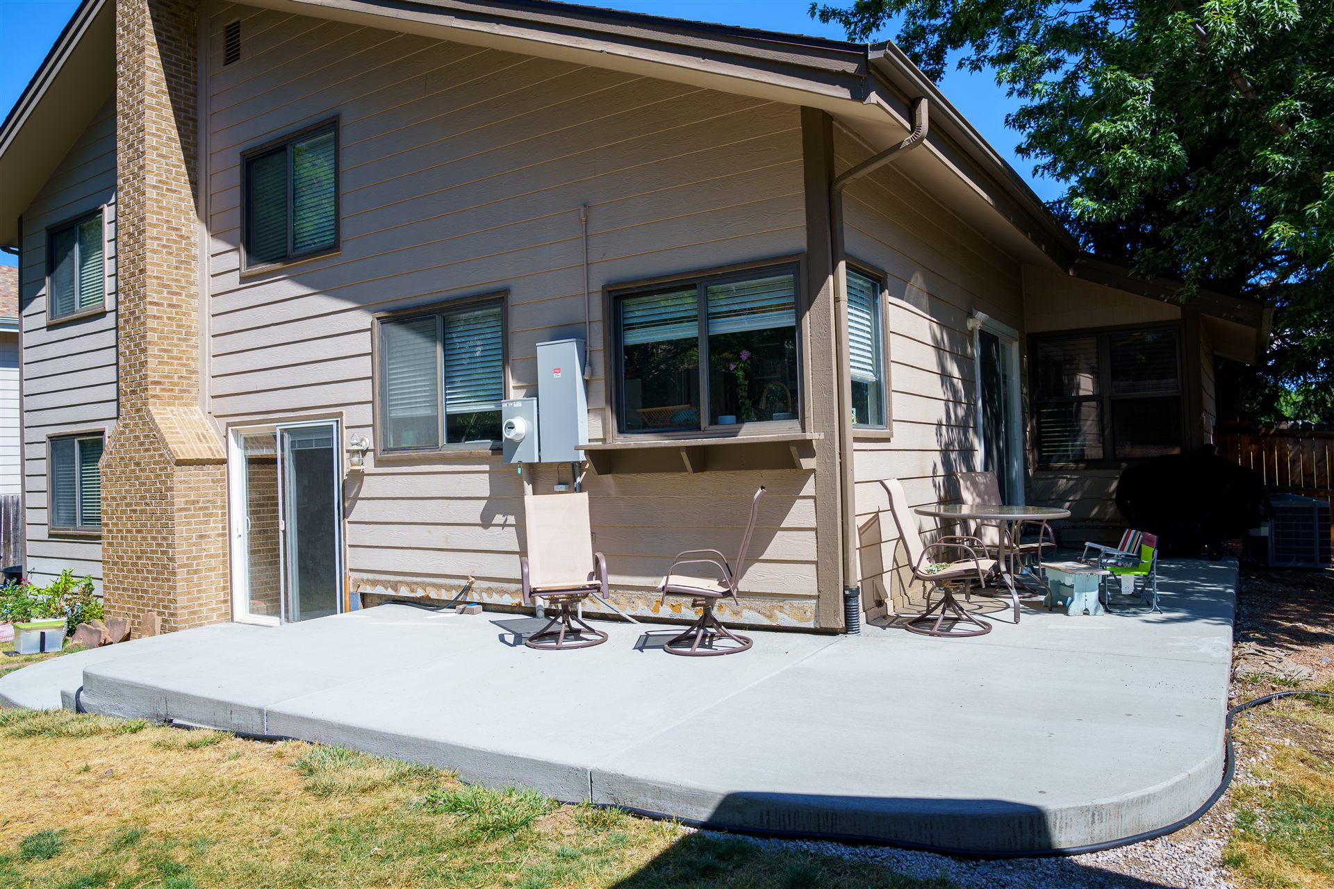 New concrete patio and steps behind a home with a shed