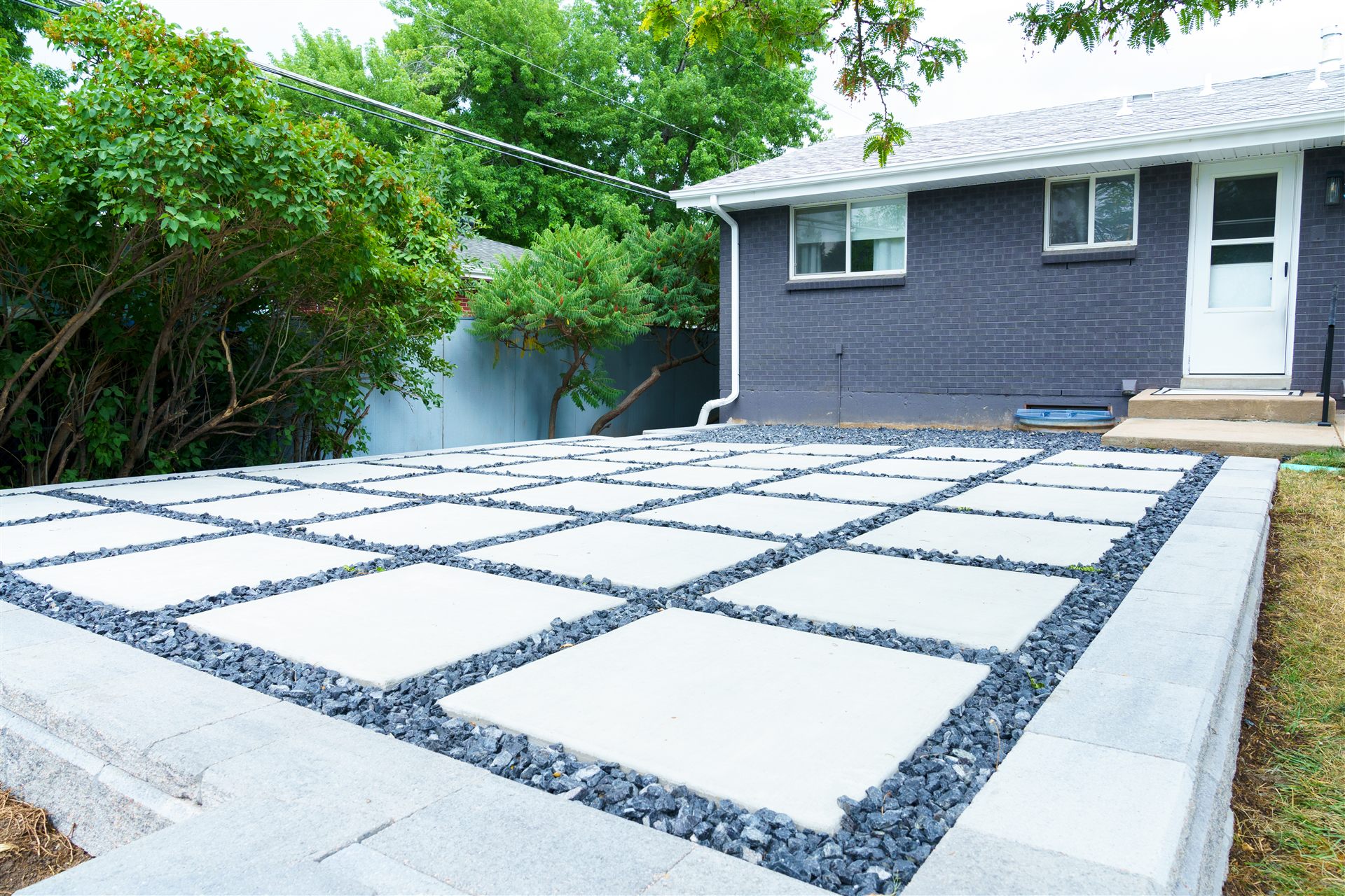 Large concrete slabs set in black rock on a raised patio