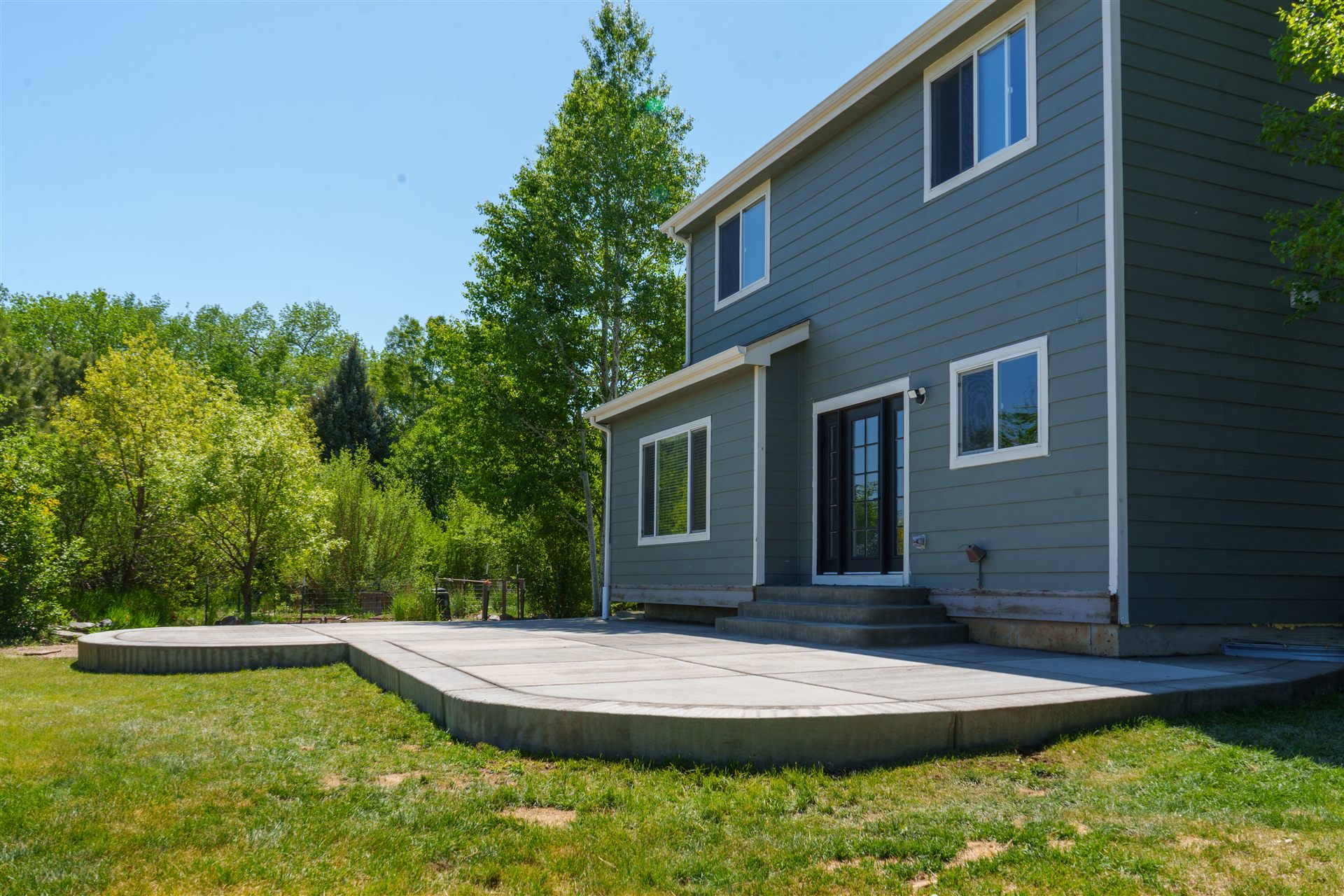 Curved concrete patio wrapping the back of a two-story home