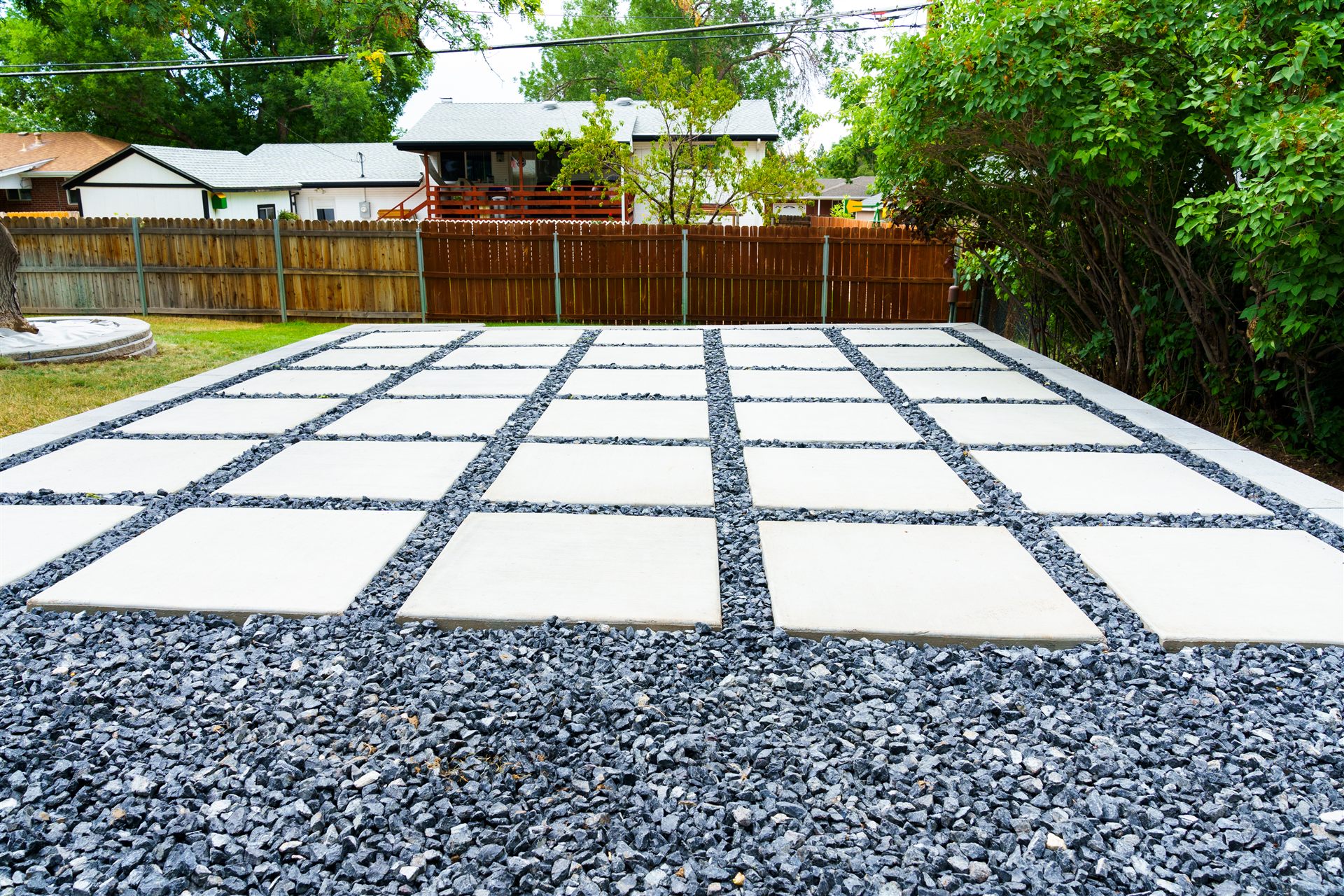 Modern concrete slab patio with black rock joints