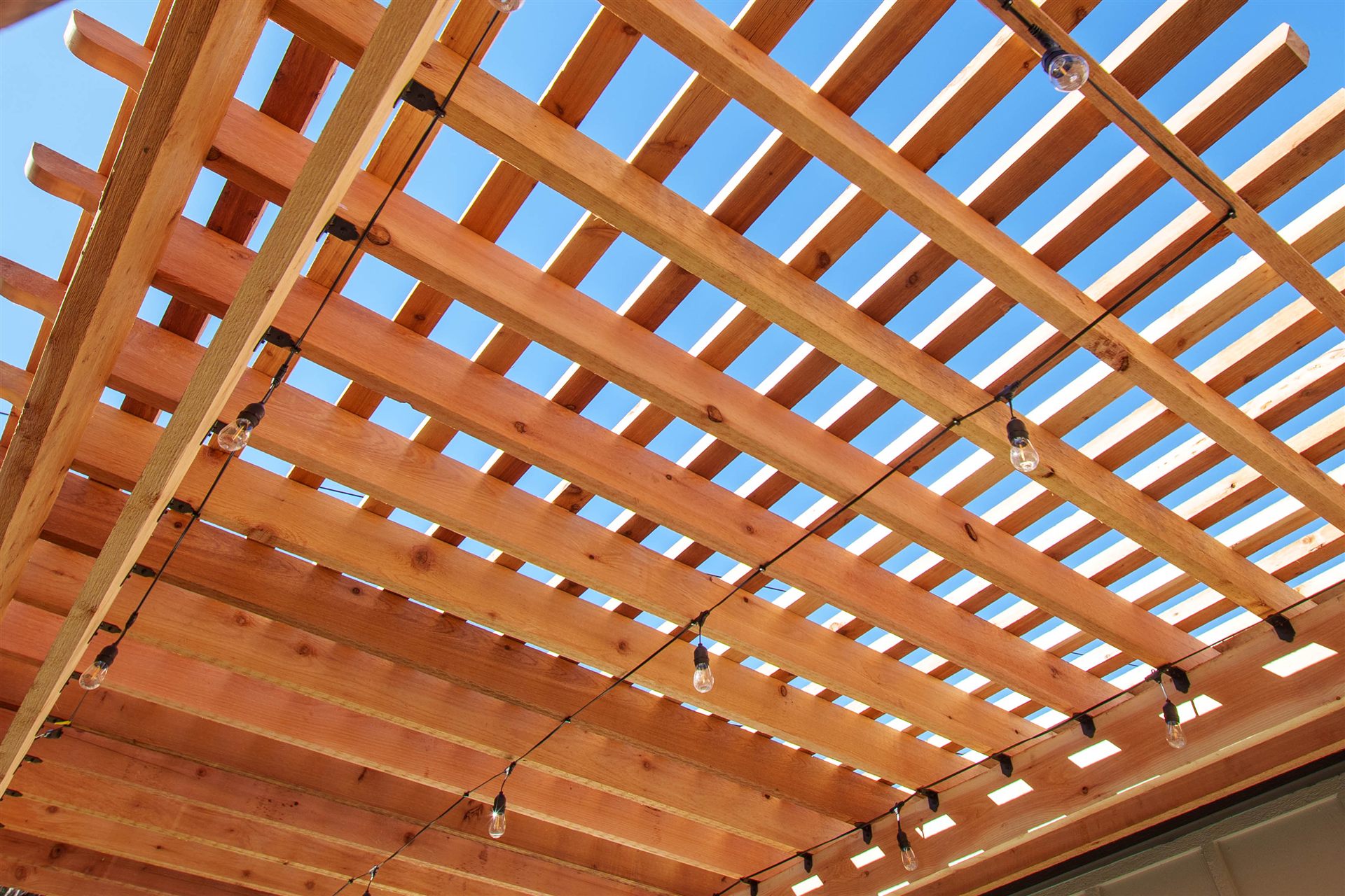 String lights hung under the rafters of a wood pergola