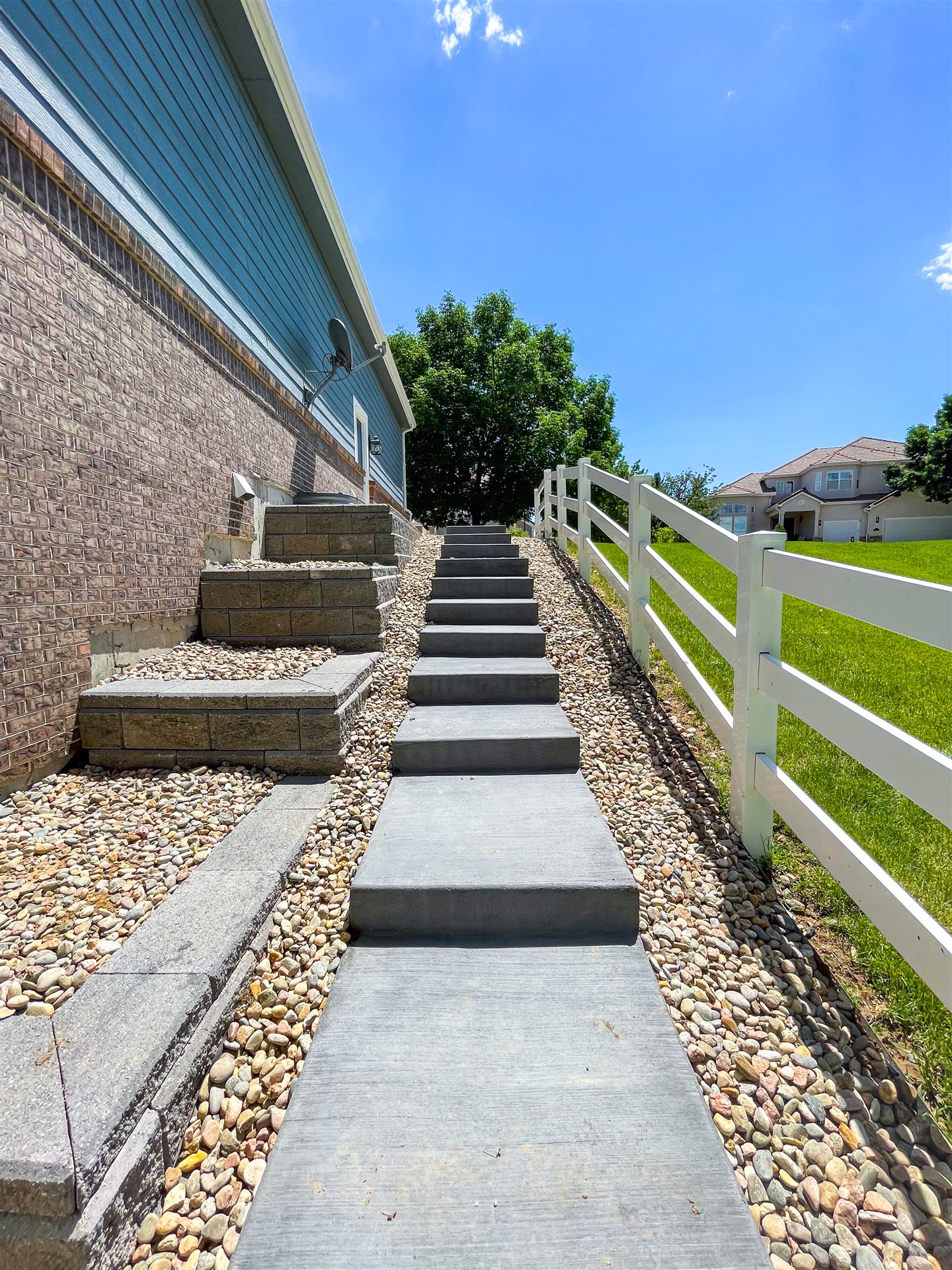 Concrete steps climbing a sloped side yard with river rock in Westminster